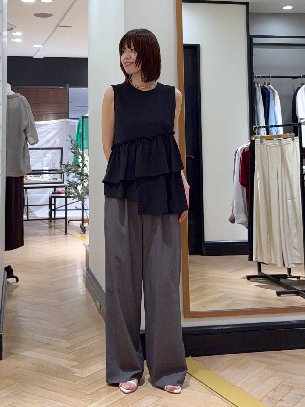 ブラック系のショルダーバッグ、ホワイト系のサンダル、グレー系のスラックスを着用したレディースの夏コーディネートの4枚目の写真