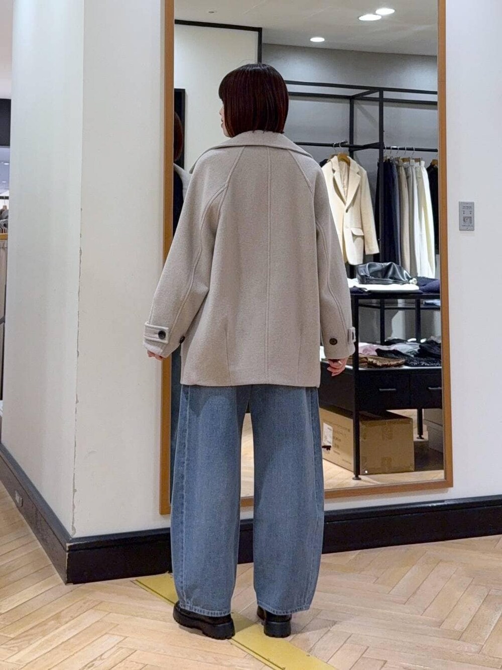 ベージュ系のピーコート、ブルー系のデニムパンツ、ブラック系のカーディガン/ボレロを着用したレディースの冬コーディネートの4枚目の写真