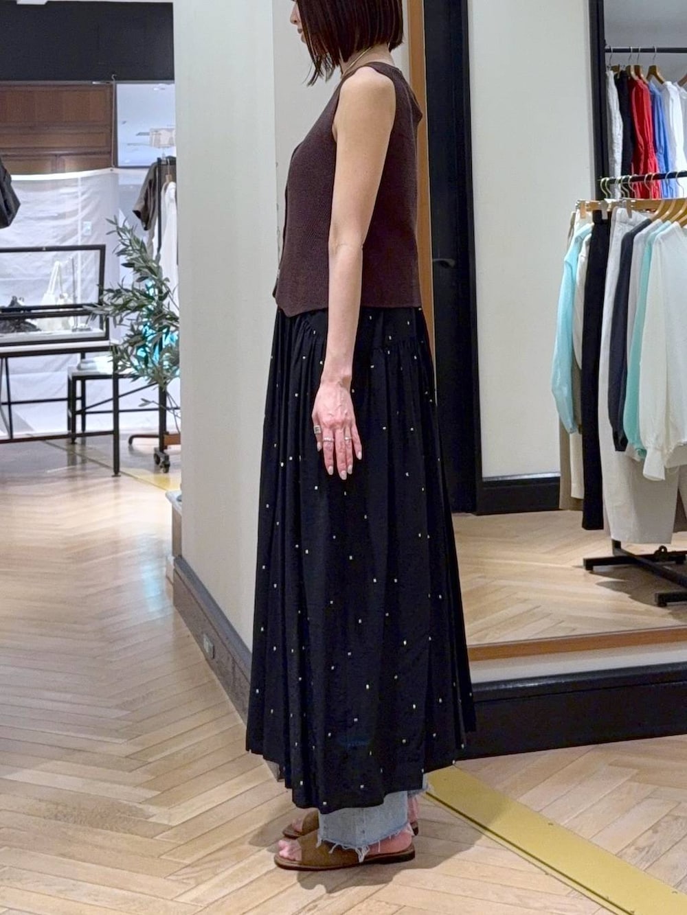 ブラック系のワンピース、ブルー系のデニムパンツ、ブラウン系のベストを着用したレディースの春コーディネートの3枚目の写真