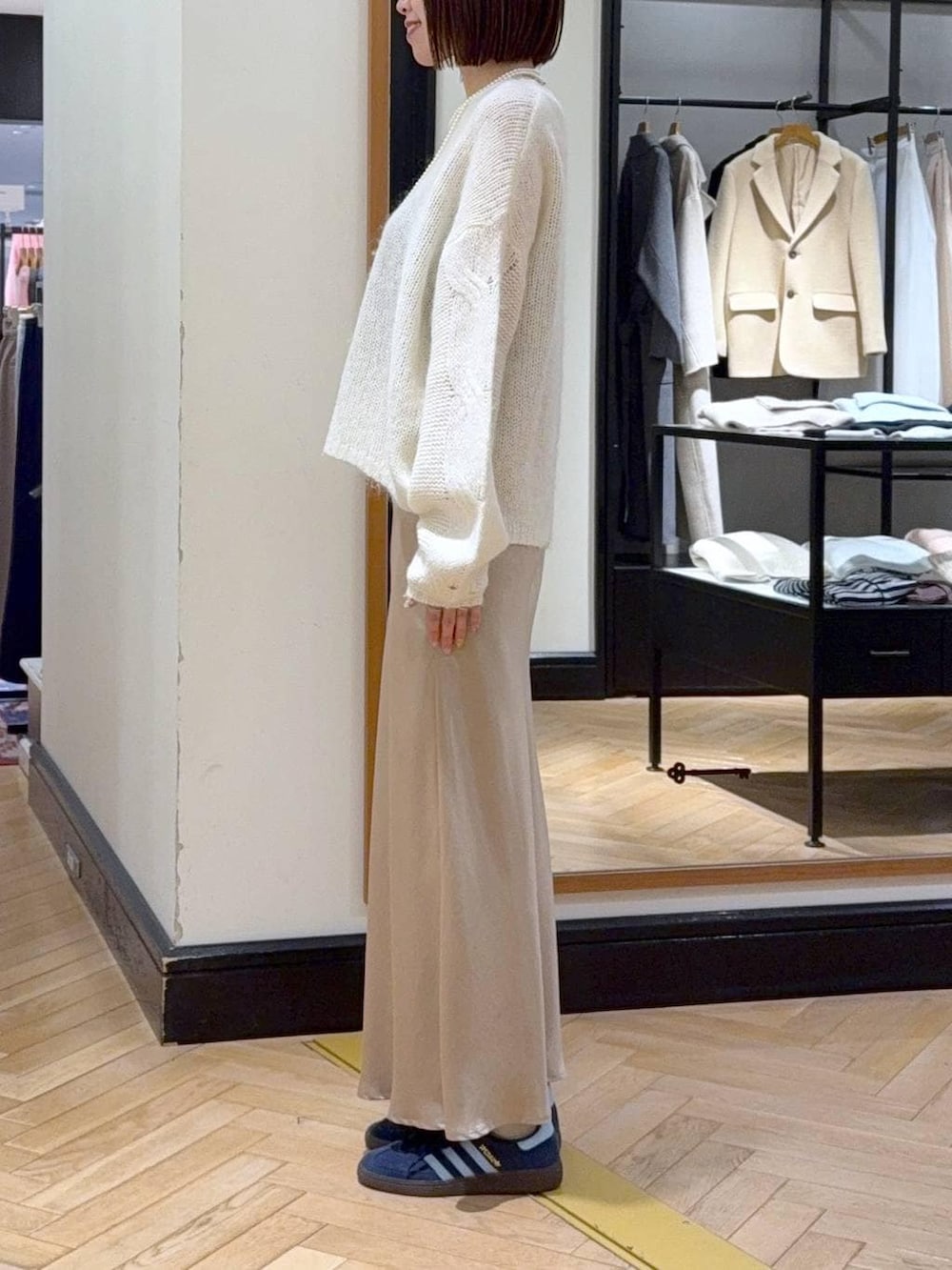 ベージュ系のスカート、ホワイト系のニット/セーター、ベージュ系のハンドバッグを着用したレディースの冬コーディネートの2枚目の写真