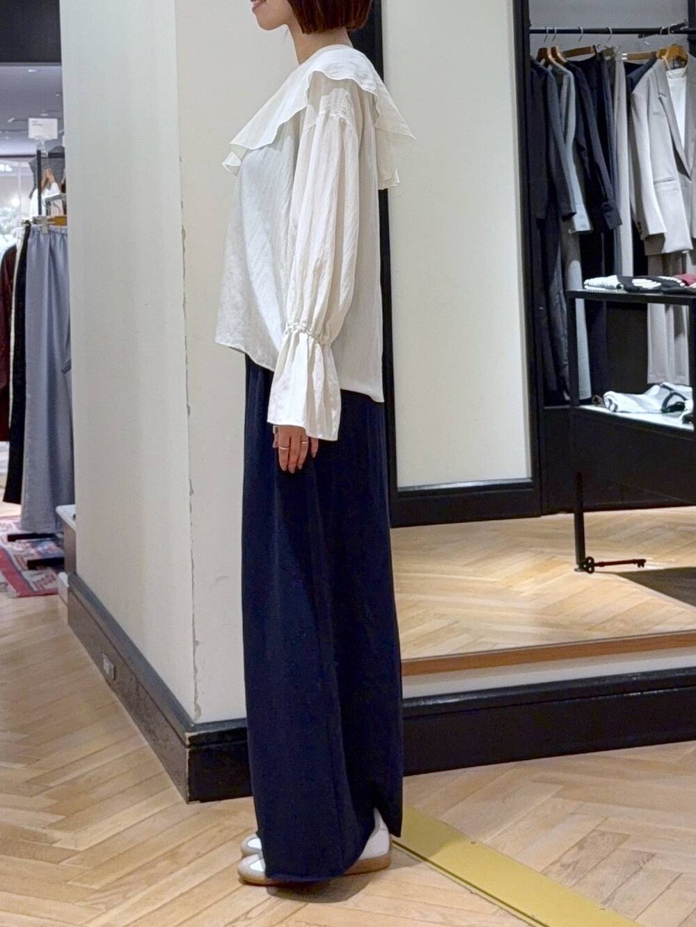 ブラック系のショルダーバッグ、ホワイト系のシャツ/ブラウス、ブルー系のスウェットパンツを着用したレディースの秋コーディネートの3枚目の写真