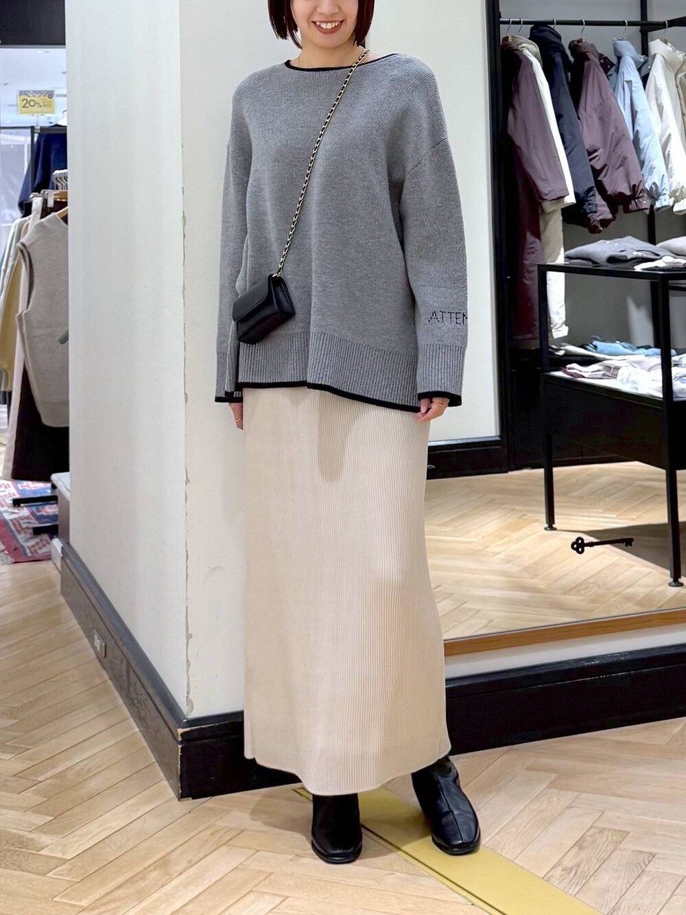 ブラック系のブーツ、ホワイト系のスカート、グレー系のニット/セーターを着用したレディースの秋コーディネートの5枚目の写真
