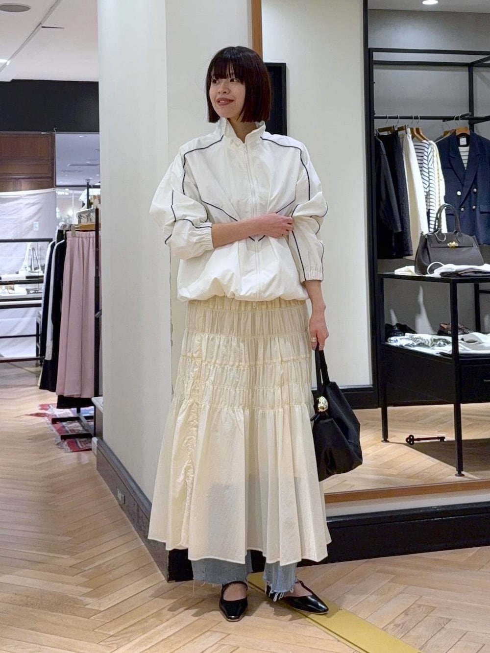 ブラック系のショルダーバッグ、ブルー系のデニムパンツ、ホワイト系のブルゾンを着用したレディースの冬コーディネートの5枚目の写真