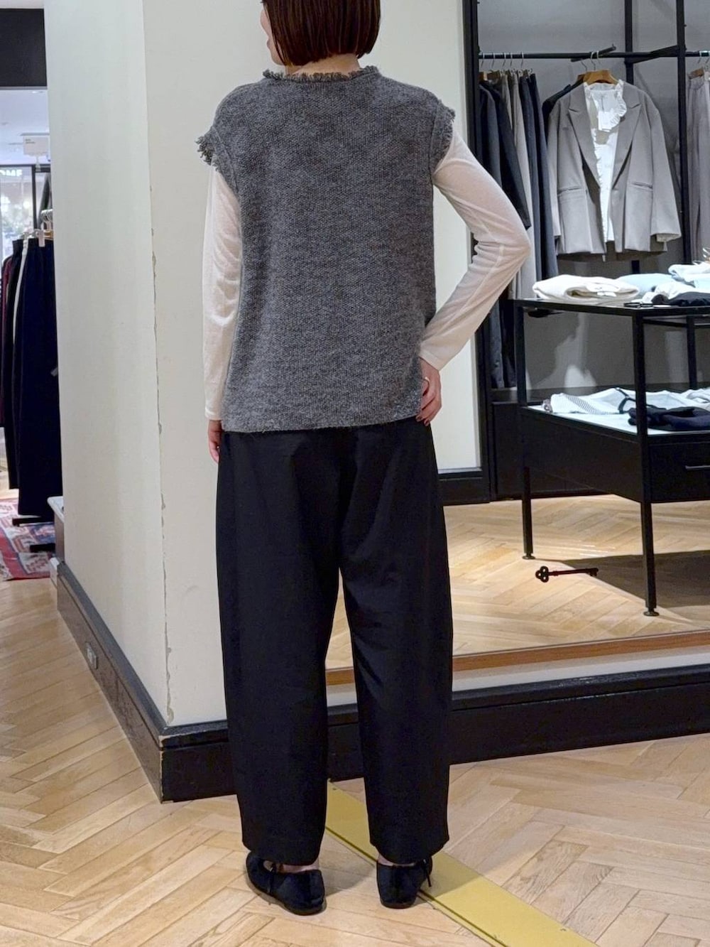 ブラック系のスラックス、グレー系のベスト、ホワイト系のTシャツ/カットソーを着用したレディースの秋コーディネートの4枚目の写真