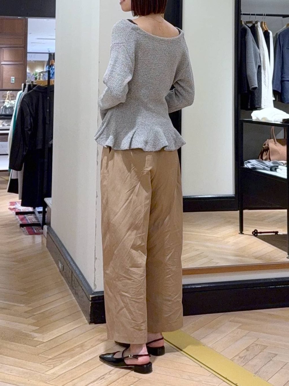 グレー系のキャミソール、ブラック系のショルダーバッグ、ブラウン系のチノパンツを着用したレディースの春コーディネートの3枚目の写真