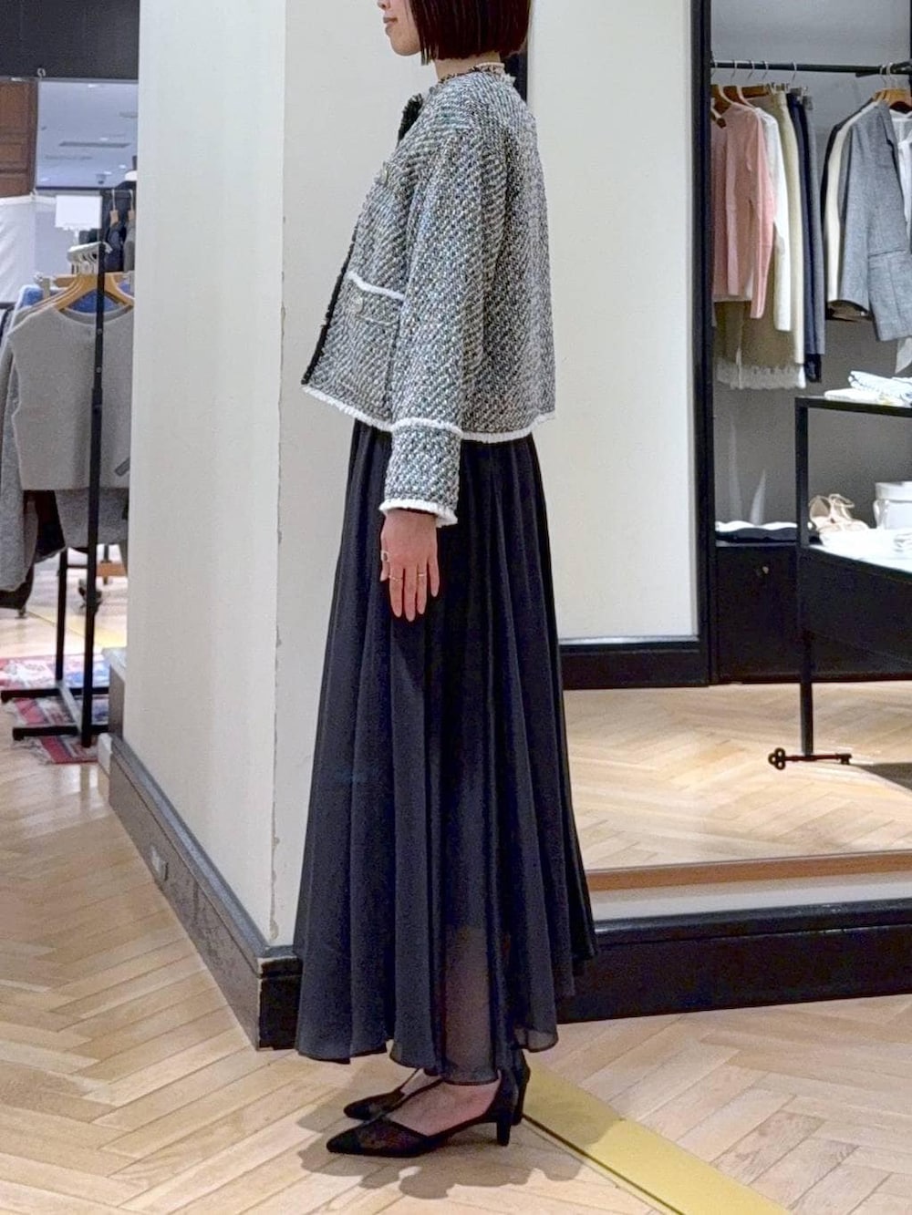 ブラック系のスカート、ブラック系のノーカラージャケット、ブラック系のパンプスを着用したレディースの冬コーディネートの3枚目の写真