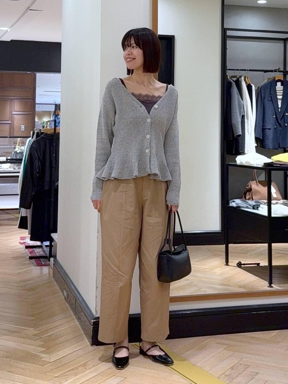 グレー系のキャミソール、ブラック系のショルダーバッグ、ブラウン系のチノパンツを着用したレディースの春コーディネートの4枚目の写真