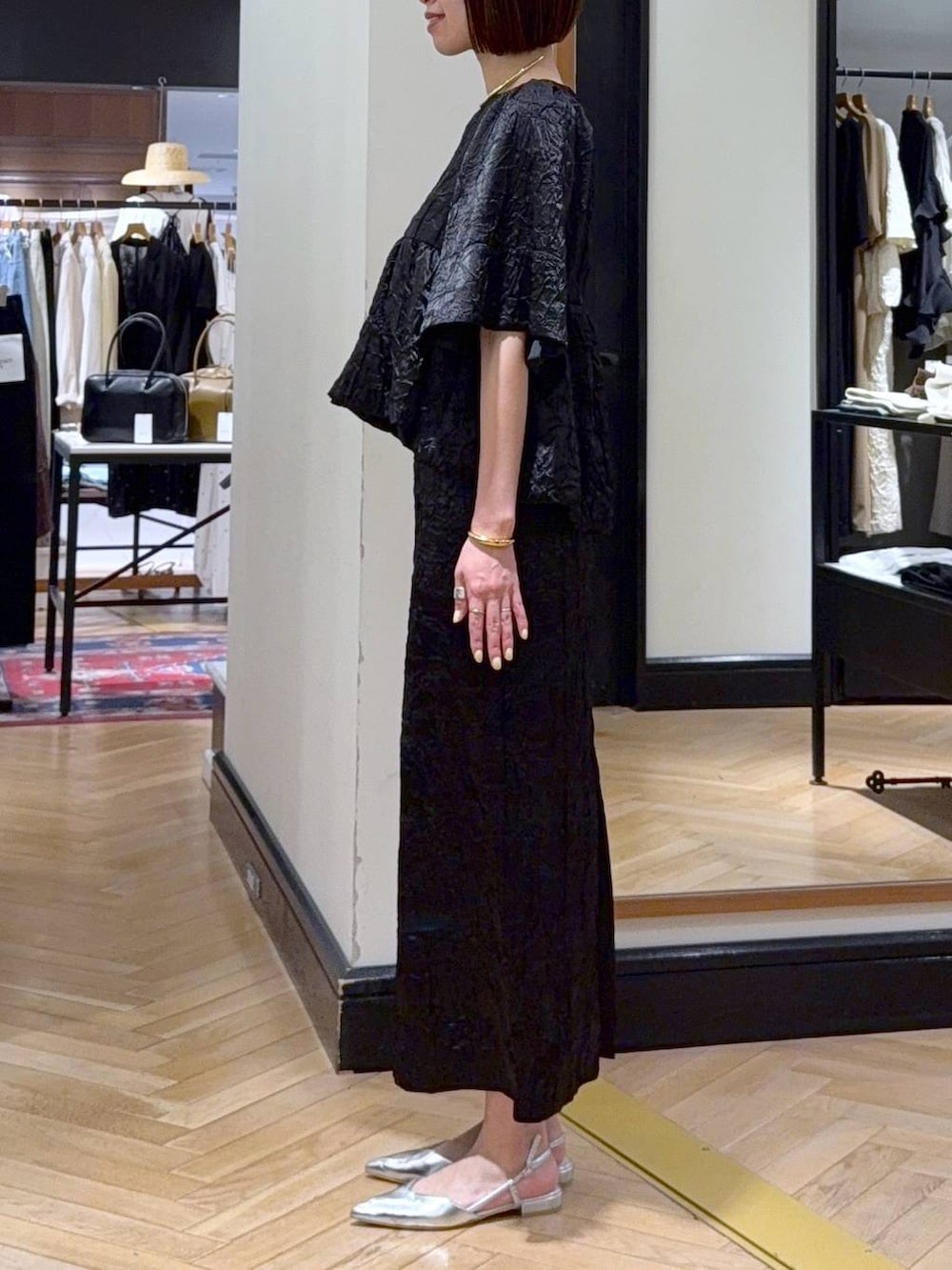 ホワイト系のハンドバッグ、シルバー系のパンプス、ブラック系のワンピースを着用したレディースの夏コーディネートの2枚目の写真