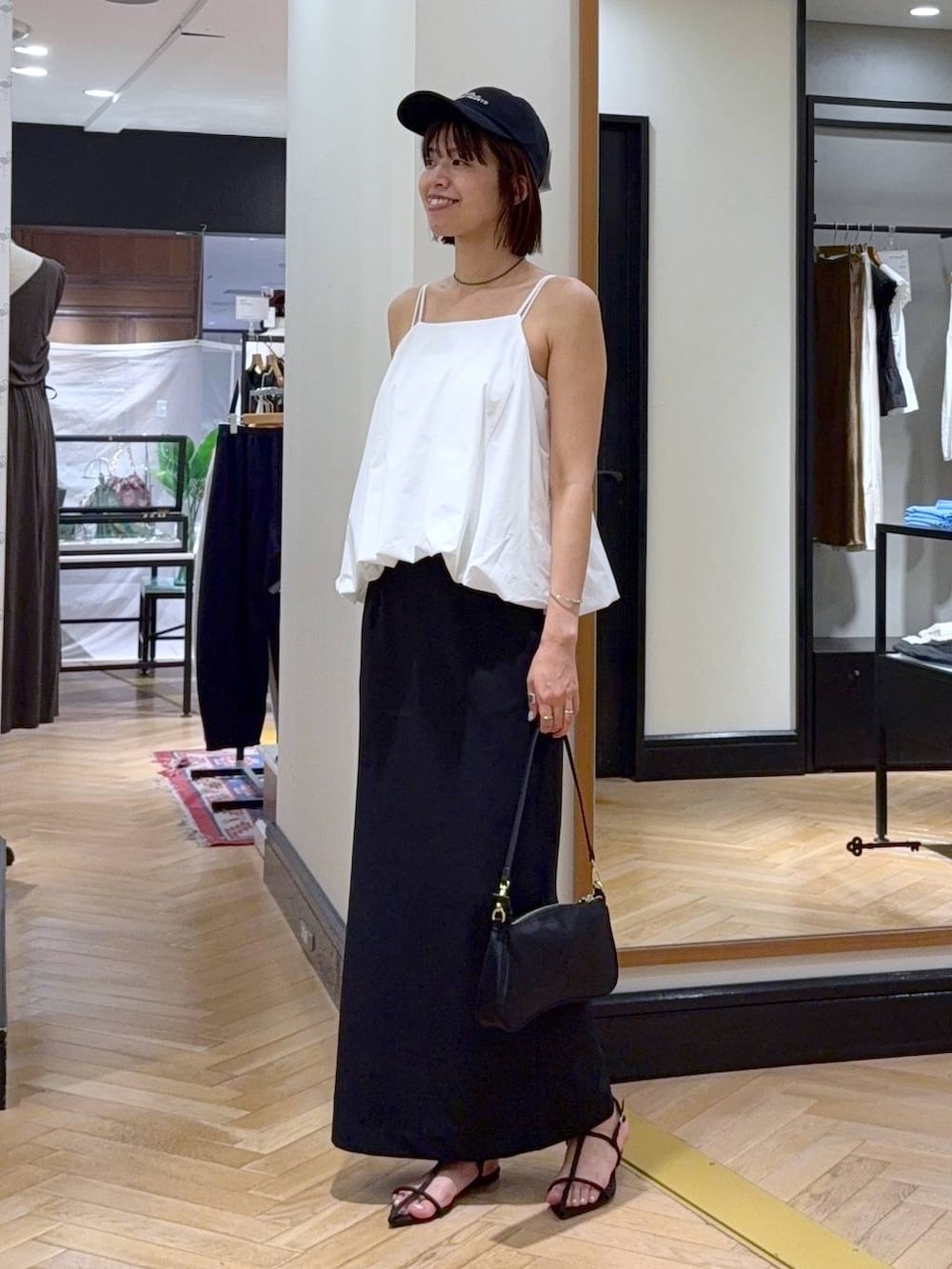 ブラウン系のサンダル、ホワイト系のセットアップ、ブラック系のショルダーバッグを着用したレディースの夏コーディネートの3枚目の写真