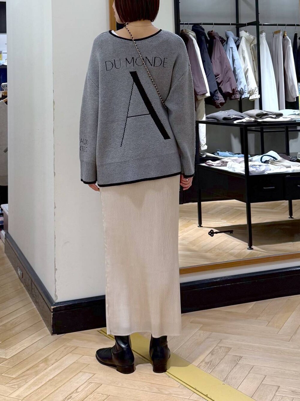 ブラック系のブーツ、ホワイト系のスカート、グレー系のニット/セーターを着用したレディースの秋コーディネートの4枚目の写真