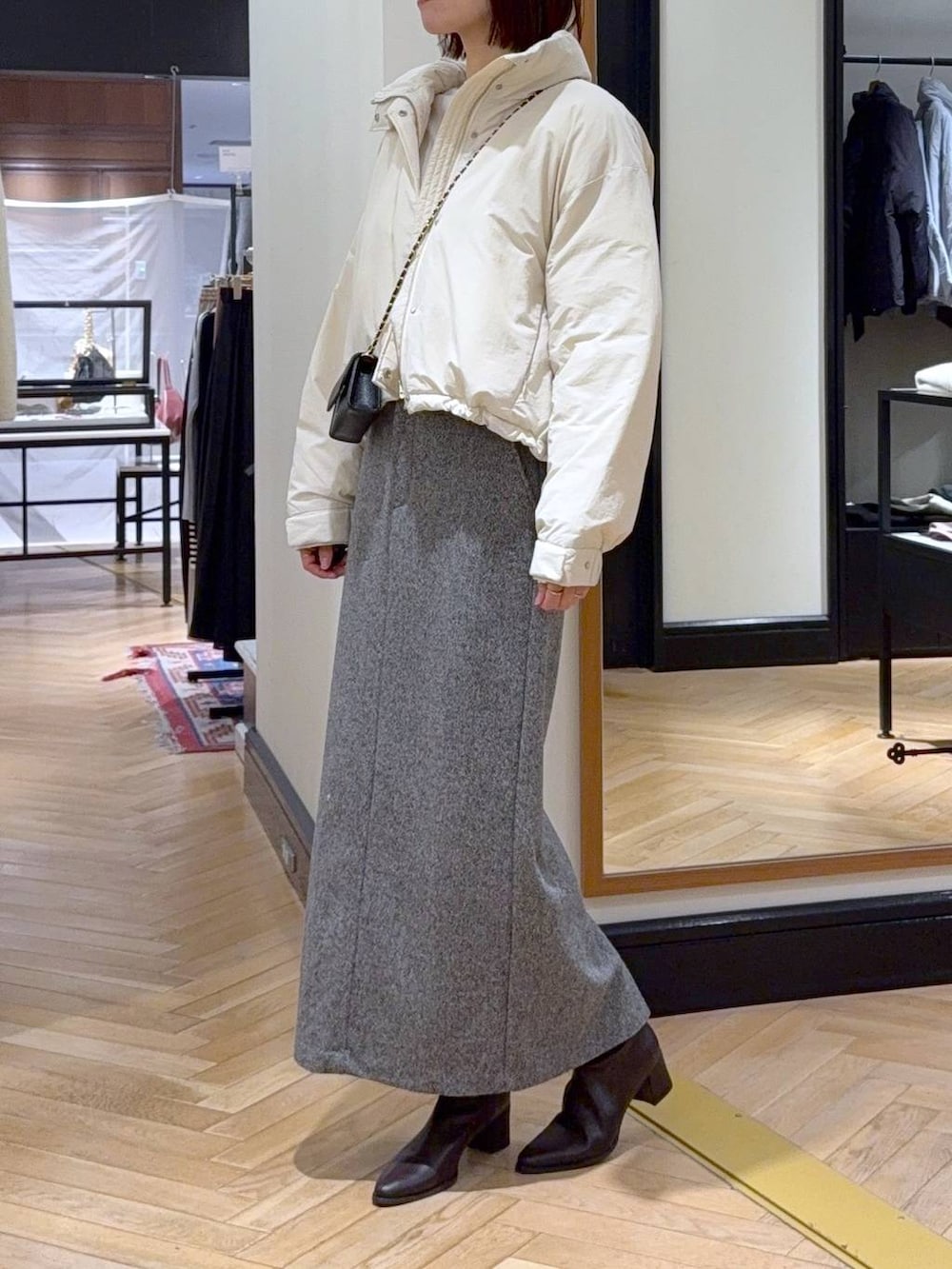 ブラウン系のブーツ、ホワイト系のブルゾン、ブラック系のスカートを着用したレディースの秋コーディネートの2枚目の写真