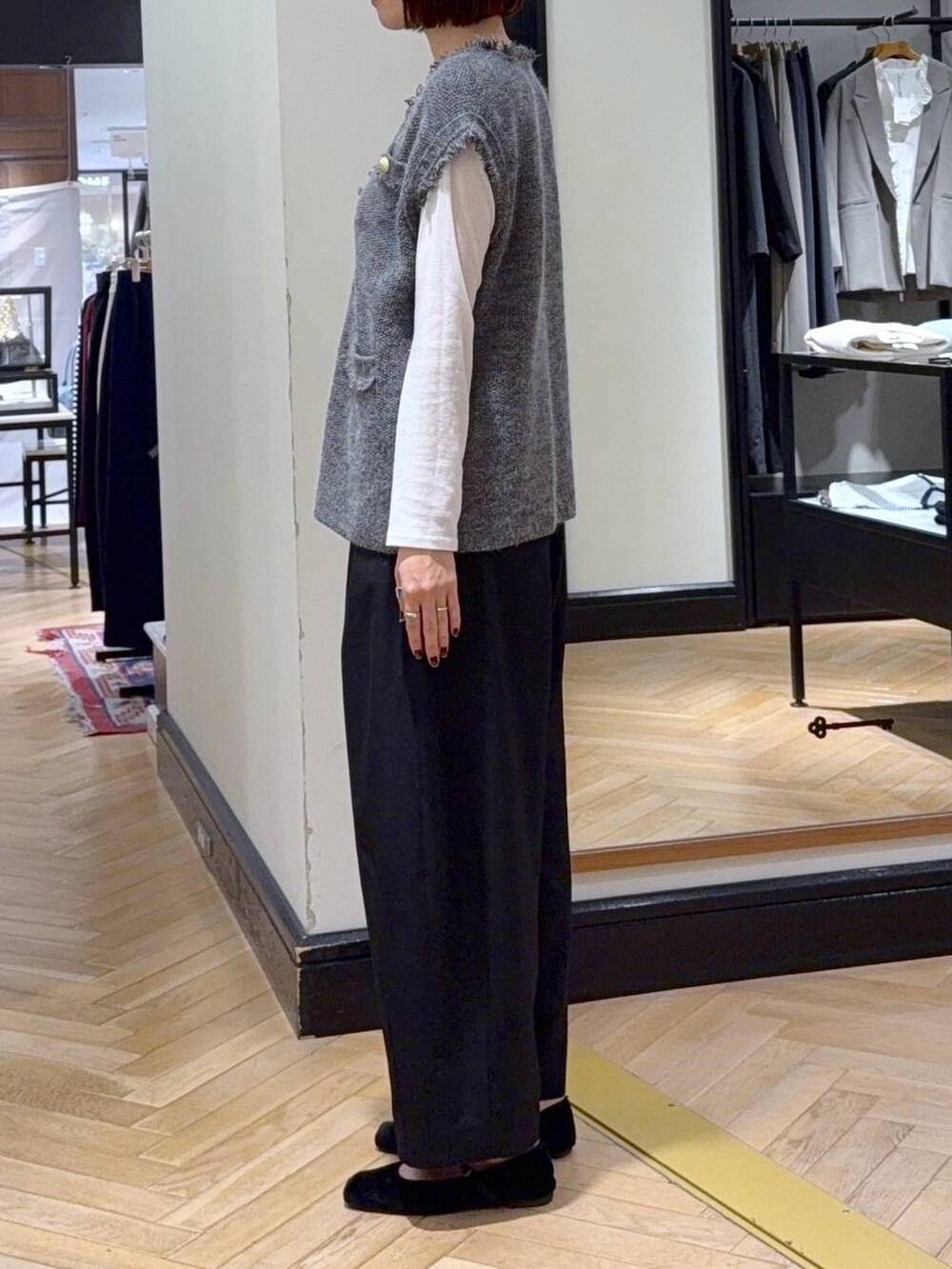 ブラック系のスラックス、グレー系のベスト、ホワイト系のTシャツ/カットソーを着用したレディースの秋コーディネートの2枚目の写真