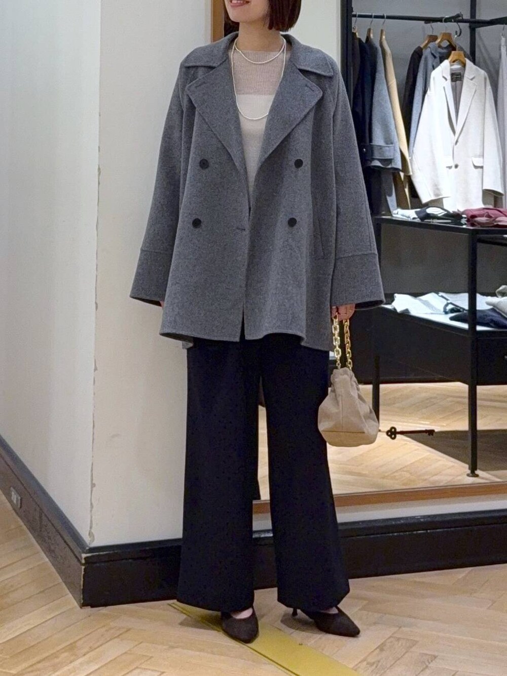 グレー系のその他アウター、ホワイト系のニット/セーター、ブラック系のスラックスを着用したレディースの秋コーディネートの2枚目の写真