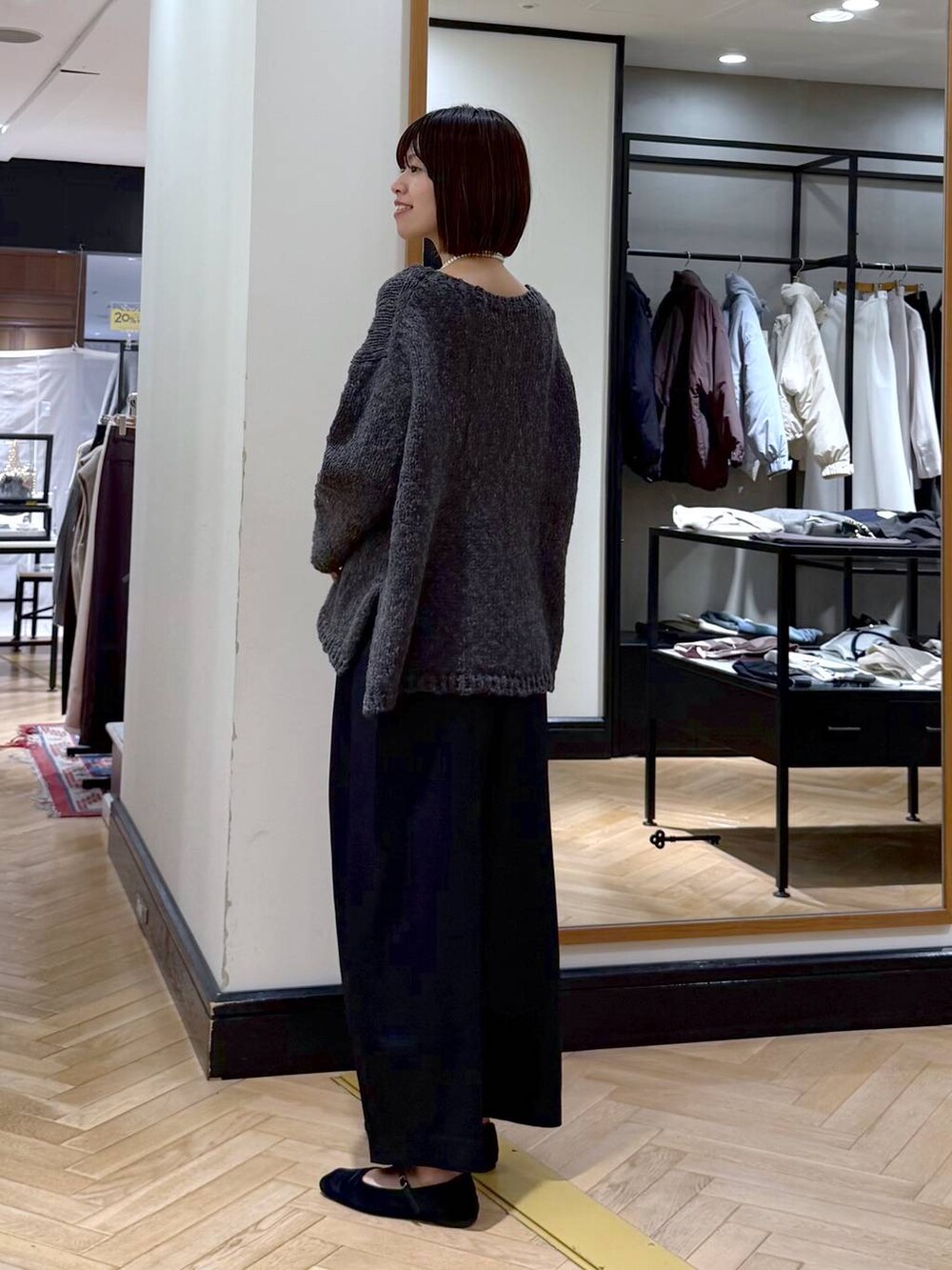 ブラック系のスラックス、グレー系のニット/セーター、ブラック系のショルダーバッグを着用したレディースの秋コーディネートの3枚目の写真