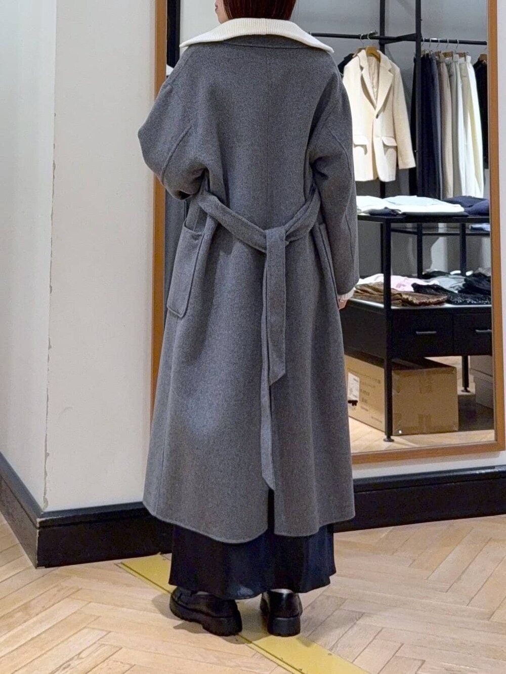 グレー系のステンカラーコート、ブルー系のスカート、ブラック系のショルダーバッグを着用したレディースの冬コーディネートの5枚目の写真