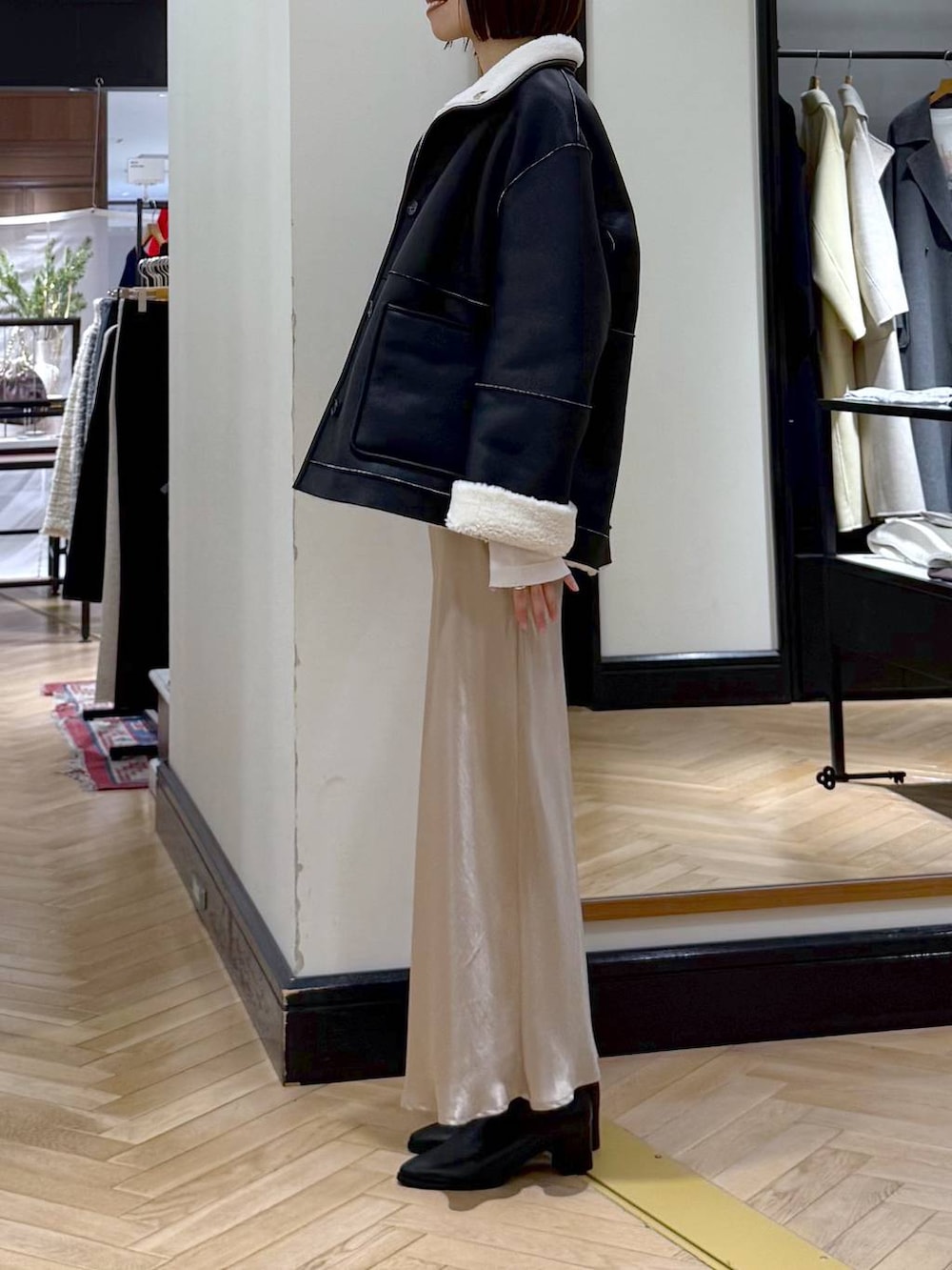 ブラック系のブーツ、ベージュ系のスカート、ブラック系のその他アウターを着用したレディースの冬コーディネートの4枚目の写真