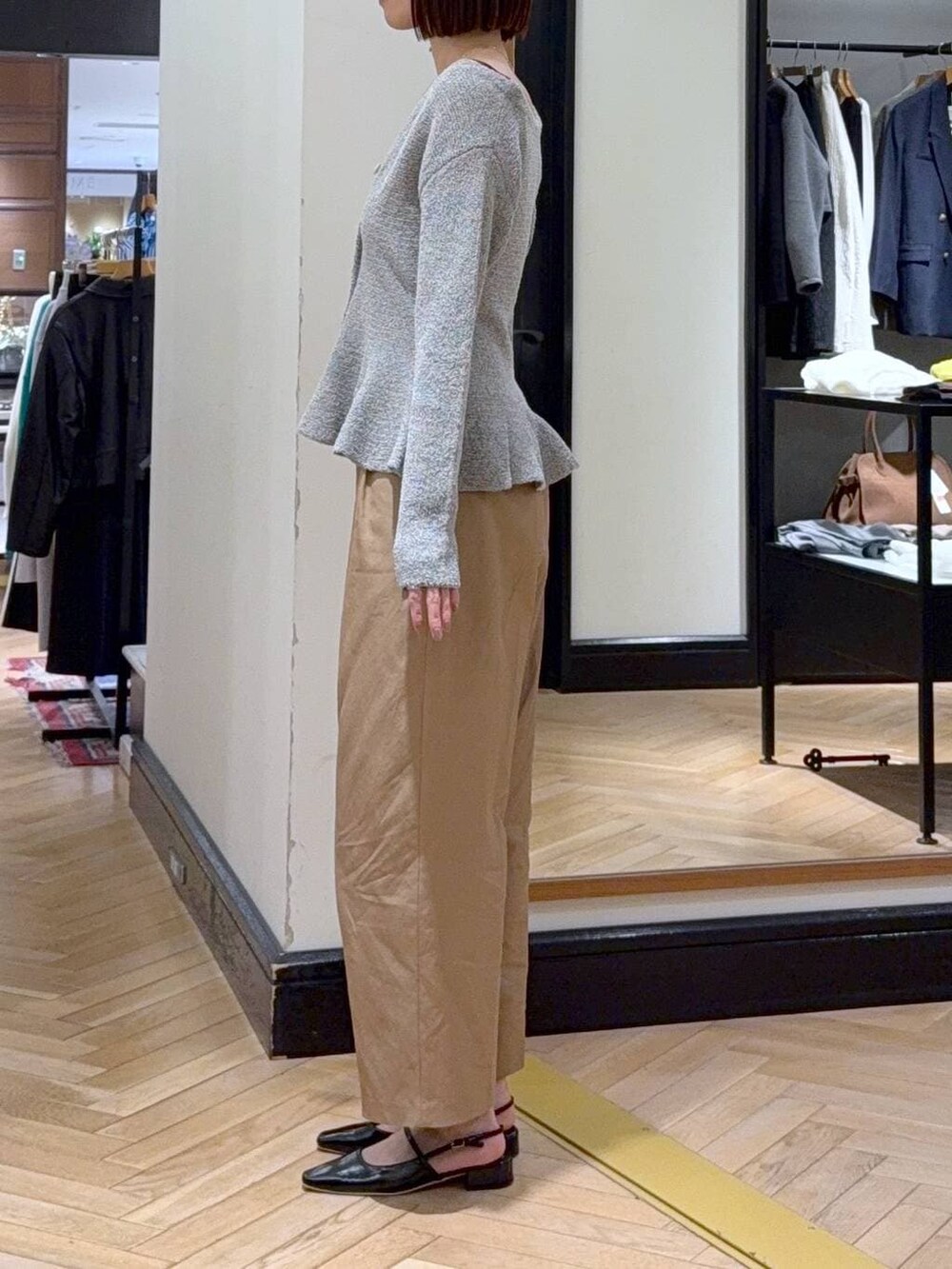 グレー系のキャミソール、ブラック系のショルダーバッグ、ブラウン系のチノパンツを着用したレディースの春コーディネートの2枚目の写真