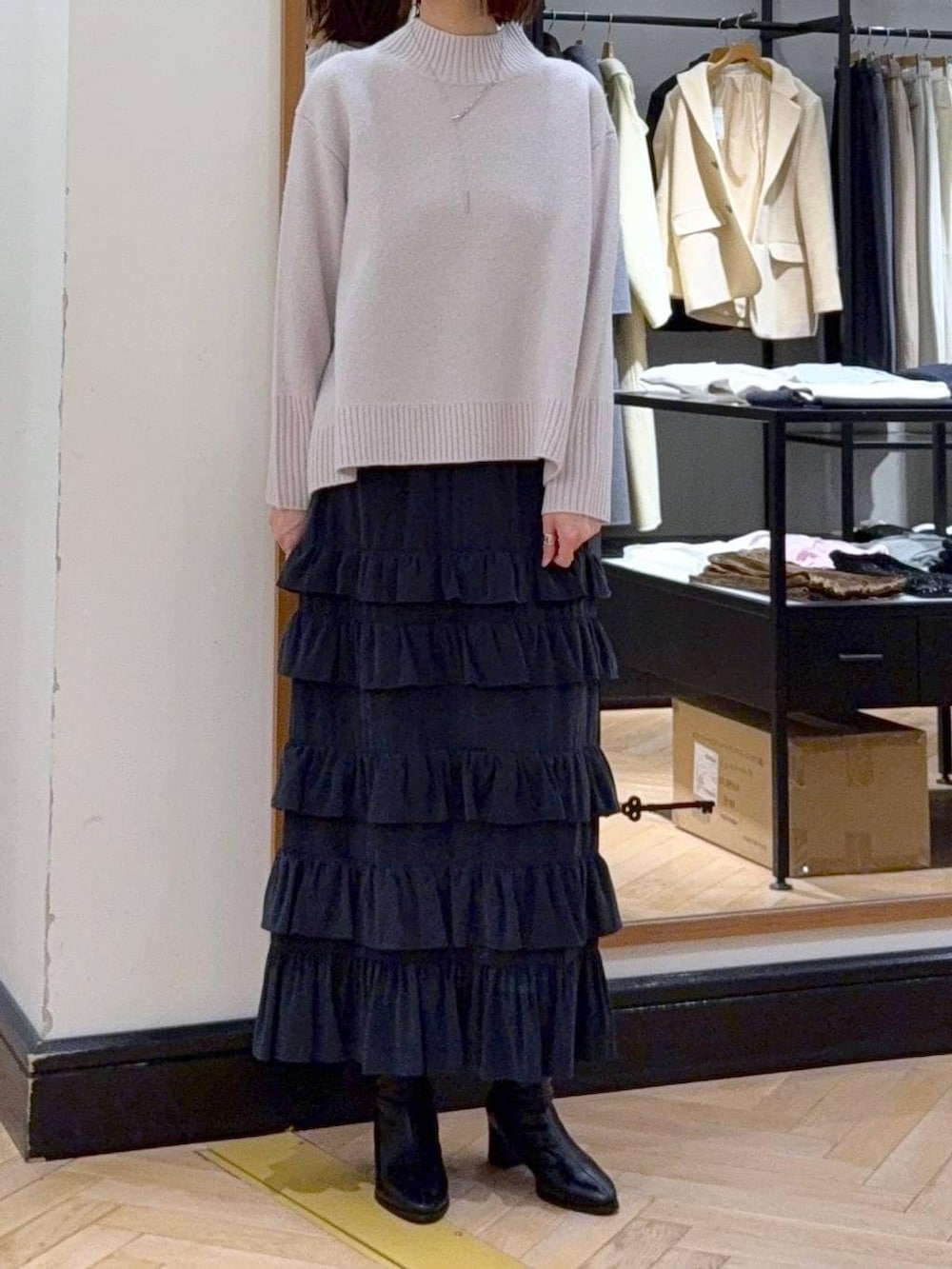 ブラック系のブーツ、グレー系のニット/セーター、ブラック系のスカートを着用したレディースの冬コーディネートの2枚目の写真