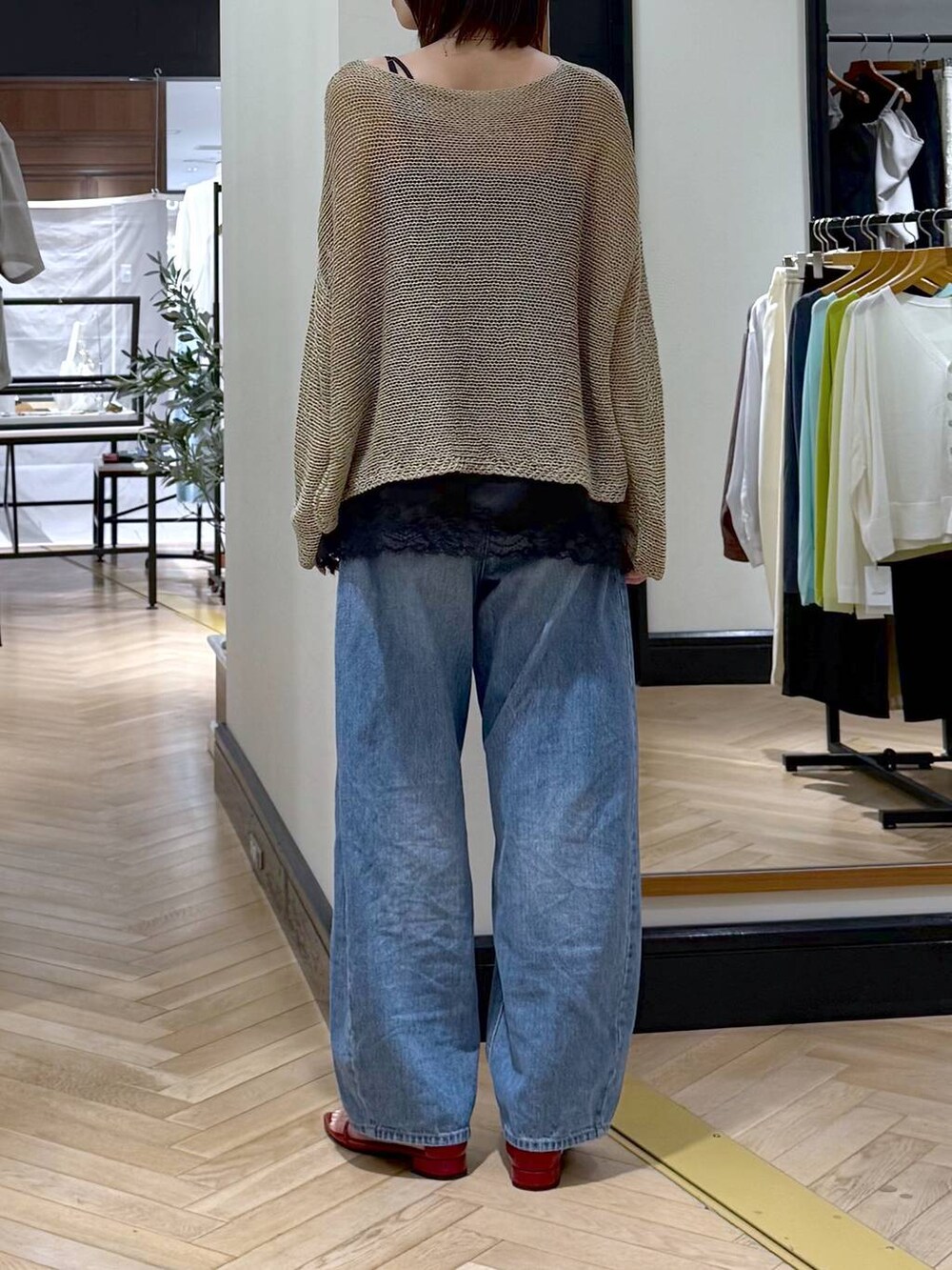 ブルー系のデニムパンツ、レッド系のサンダル、ベージュ系のニット/セーターを着用したレディースの夏コーディネートの3枚目の写真