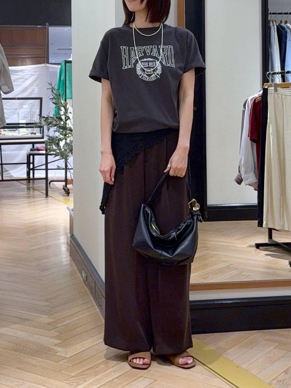 ブラウン系のスラックス、ブラック系のショルダーバッグ、グレー系のTシャツ/カットソーを着用したレディースの夏コーディネートの2枚目の写真