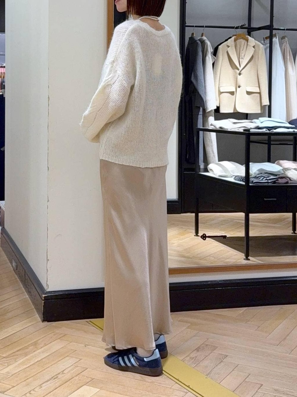 ベージュ系のスカート、ホワイト系のニット/セーター、ベージュ系のハンドバッグを着用したレディースの冬コーディネートの3枚目の写真