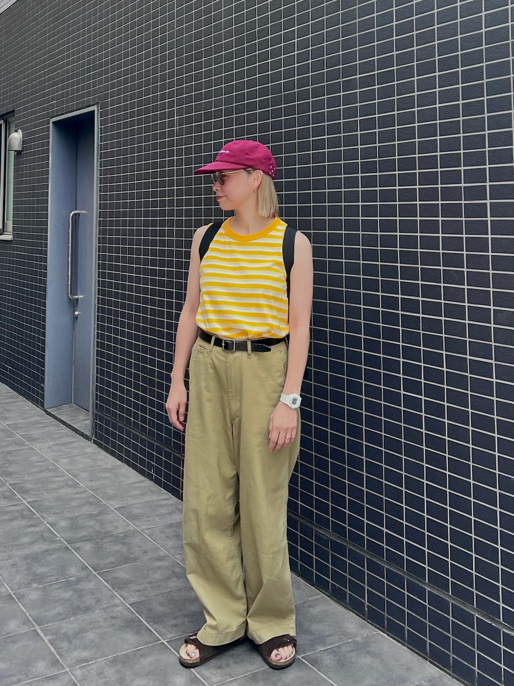 ブラウン系のサンダル、イエロー系のタンクトップ、ブラック系のバックパック/リュックを着用したレディースの夏コーディネートの2枚目の写真