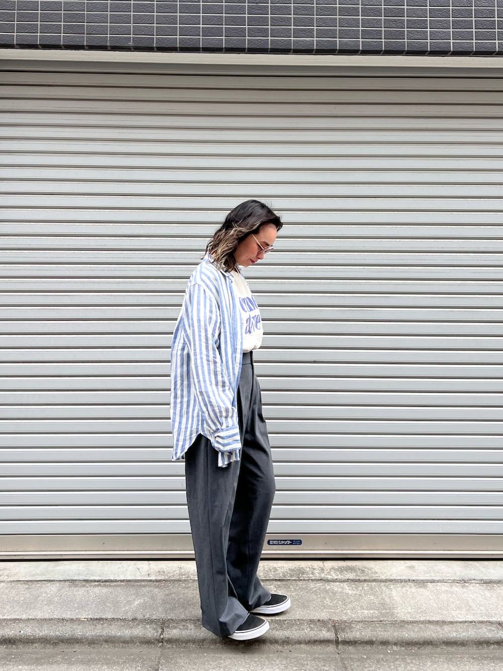 グレー系のスラックス、ブラック系のスニーカー、ブルー系のシャツ/ブラウスを着用したレディースの春コーディネートの2枚目の写真