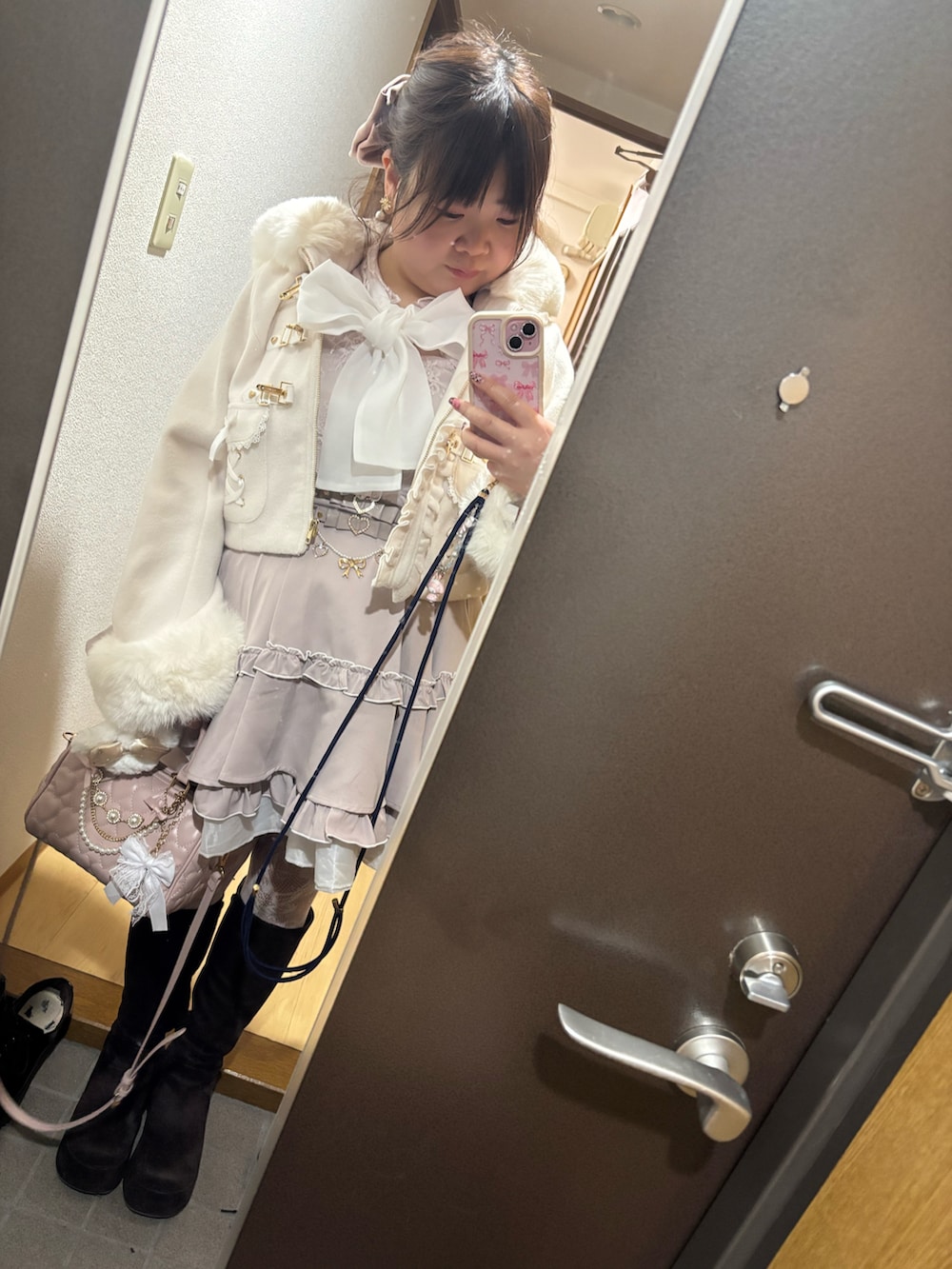 ホワイト系のその他アウター、ピンク系のスカート、ピンク系のハンドバッグを着用したレディースの冬コーディネートの2枚目の写真