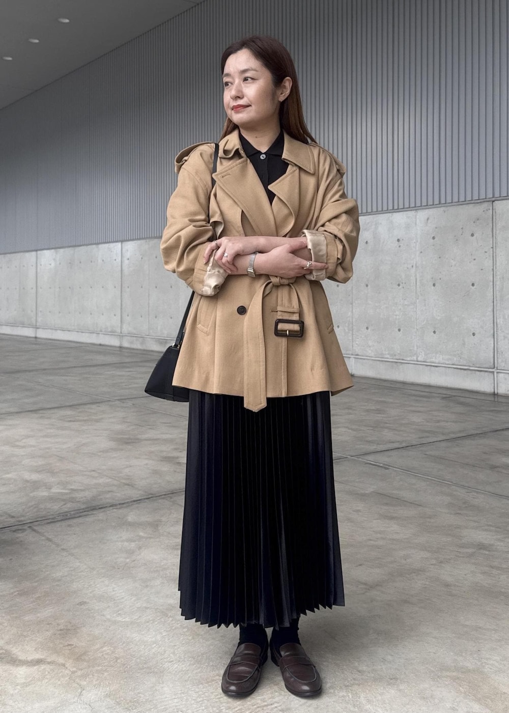 ブラック系のスカート、ブラック系のショルダーバッグ、ベージュ系のトレンチコートを着用したレディースの春コーディネートの6枚目の写真