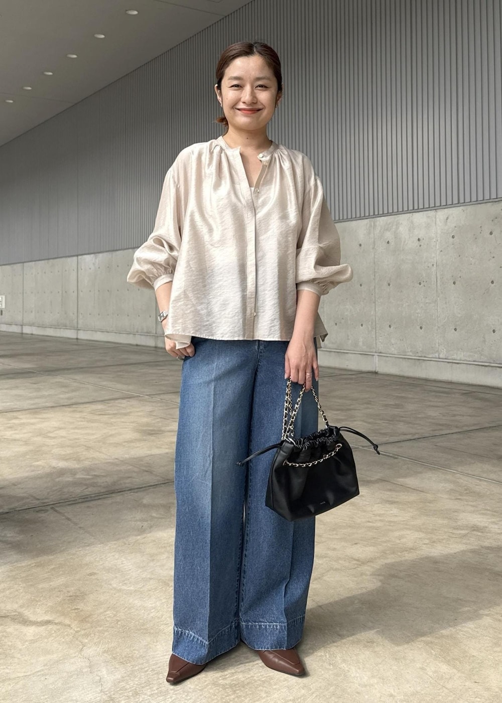 ブルー系のデニムパンツ、ブラック系のハンドバッグ、ベージュ系のシャツ/ブラウスを着用したレディースの春コーディネートの2枚目の写真