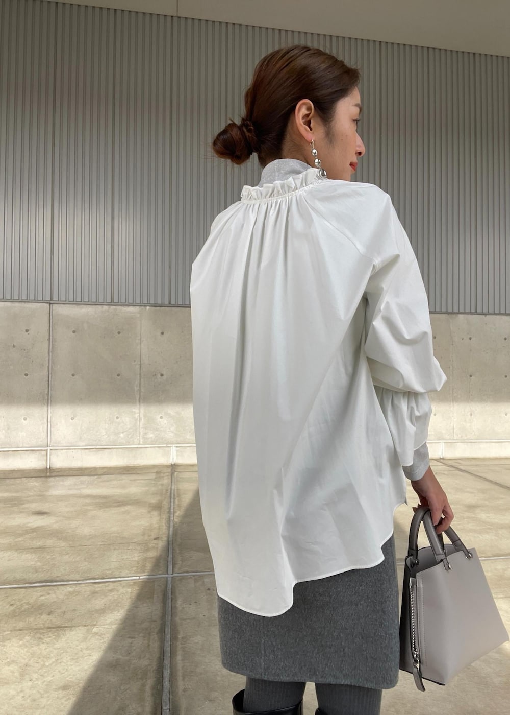 グレー系のスカート、シルバー系のTシャツ/カットソー、グレー系のピーコートを着用したレディースの冬コーディネートの5枚目の写真