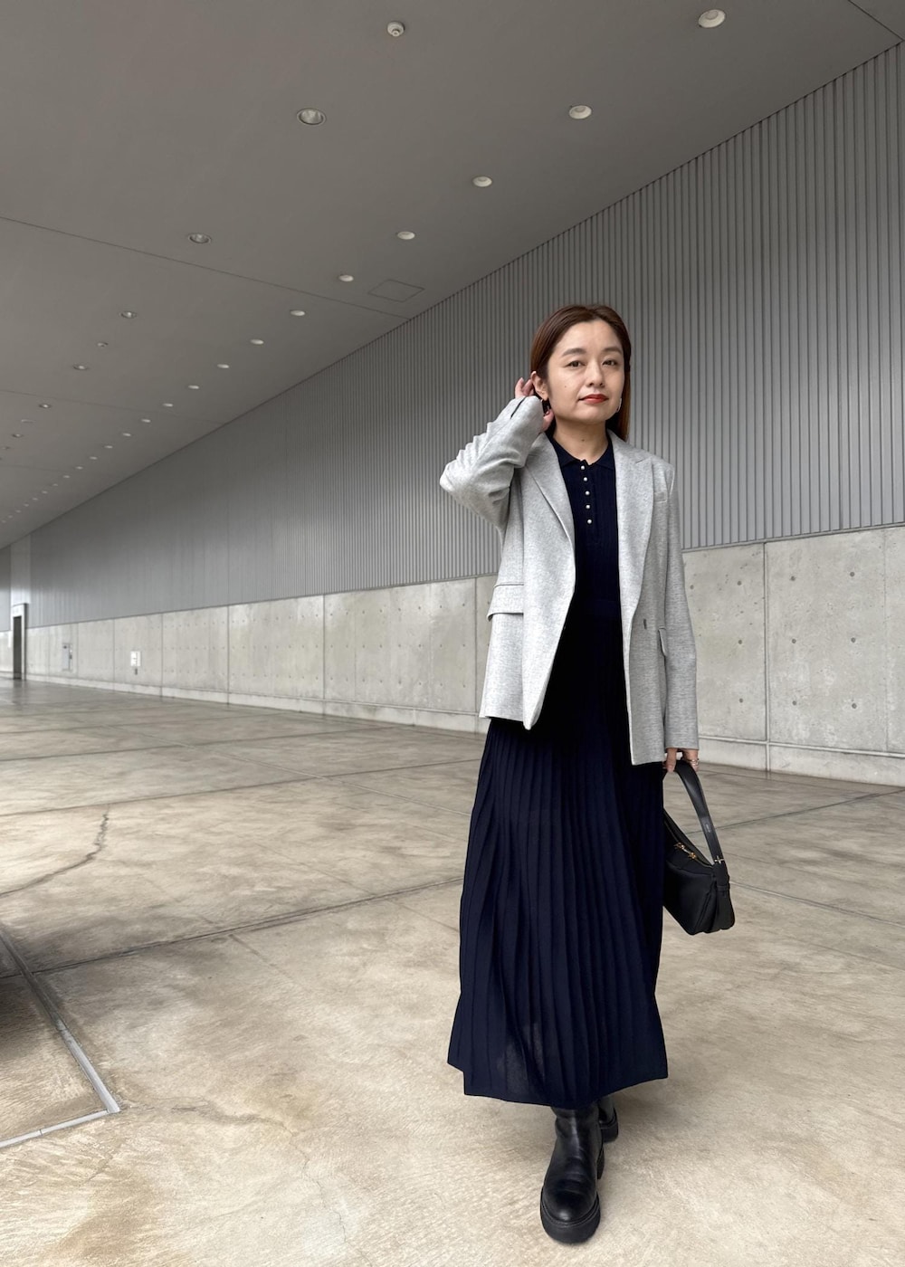 ブラック系のハンドバッグ、グレー系のテーラードジャケット、ブルー系のドレスを着用したレディースの冬コーディネートの4枚目の写真