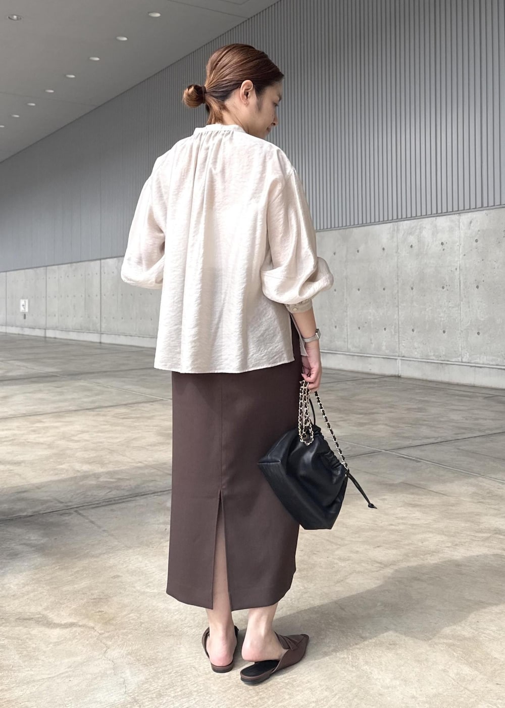 ブラック系のハンドバッグ、ブラウン系のスカート、ベージュ系のシャツ/ブラウスを着用したレディースの春コーディネートの3枚目の写真