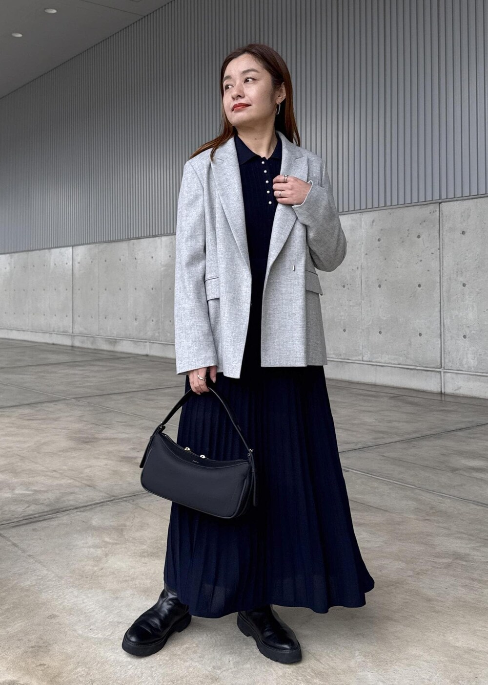 ブラック系のハンドバッグ、グレー系のテーラードジャケット、ブルー系のドレスを着用したレディースの冬コーディネートの2枚目の写真