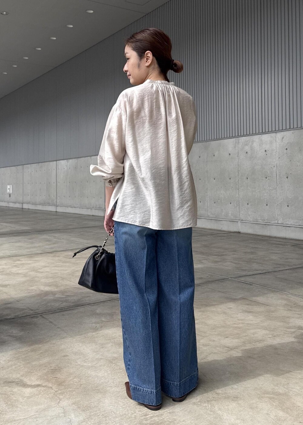 ブルー系のデニムパンツ、ブラック系のハンドバッグ、ベージュ系のシャツ/ブラウスを着用したレディースの春コーディネートの3枚目の写真