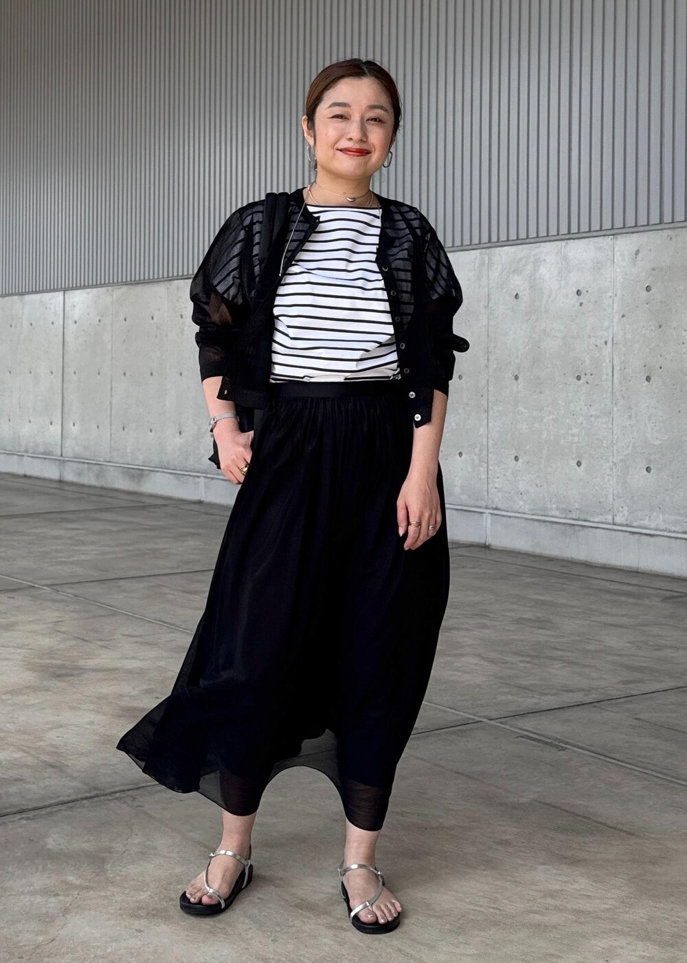 シルバー系のサンダル、ブラック系のスカート、ブラック系のカーディガン/ボレロを着用したレディースの夏コーディネートの2枚目の写真