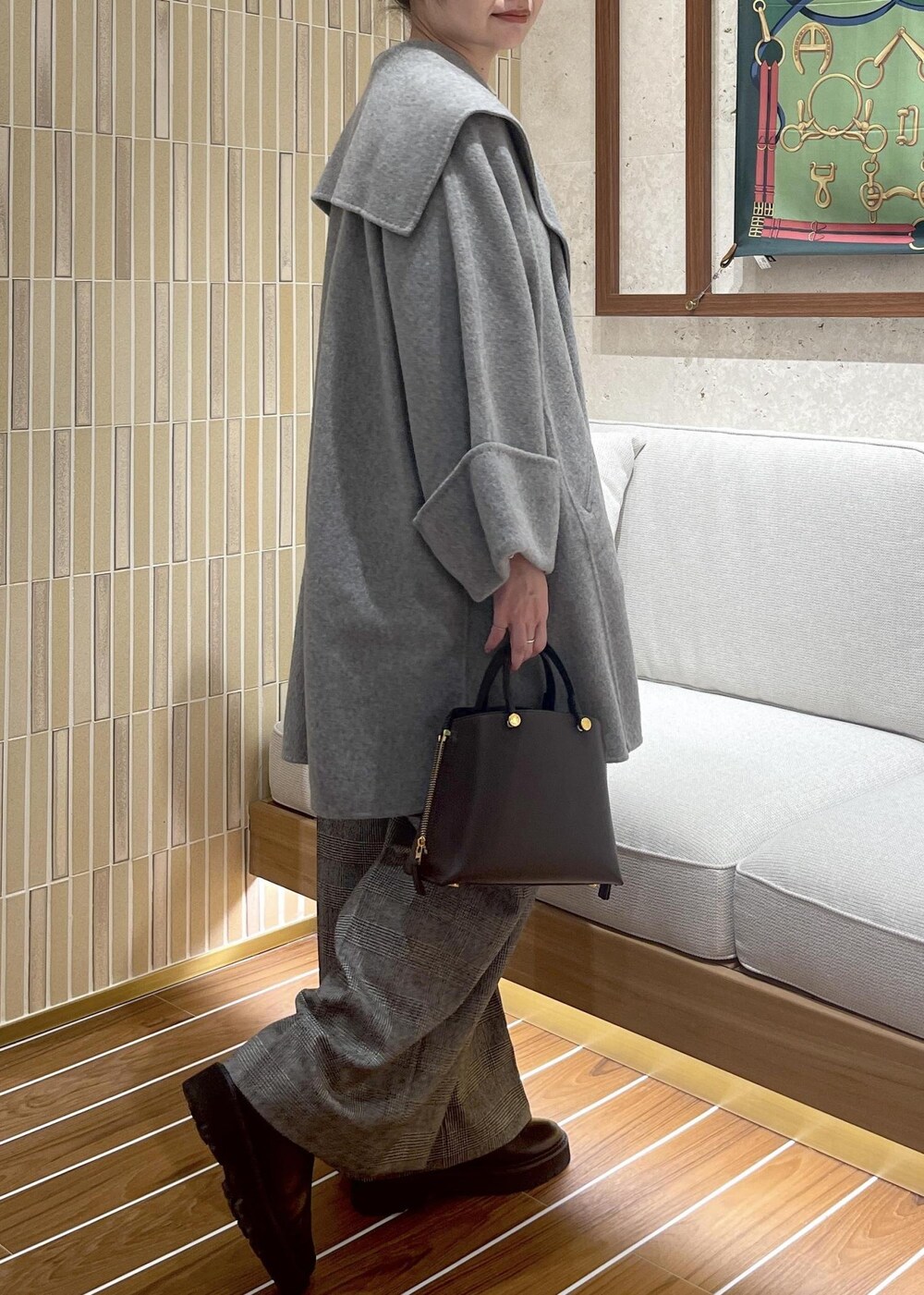 ブラウン系のハンドバッグ、グレー系のその他アウター、ブラック系のブーツを着用したレディースの秋コーディネートの4枚目の写真