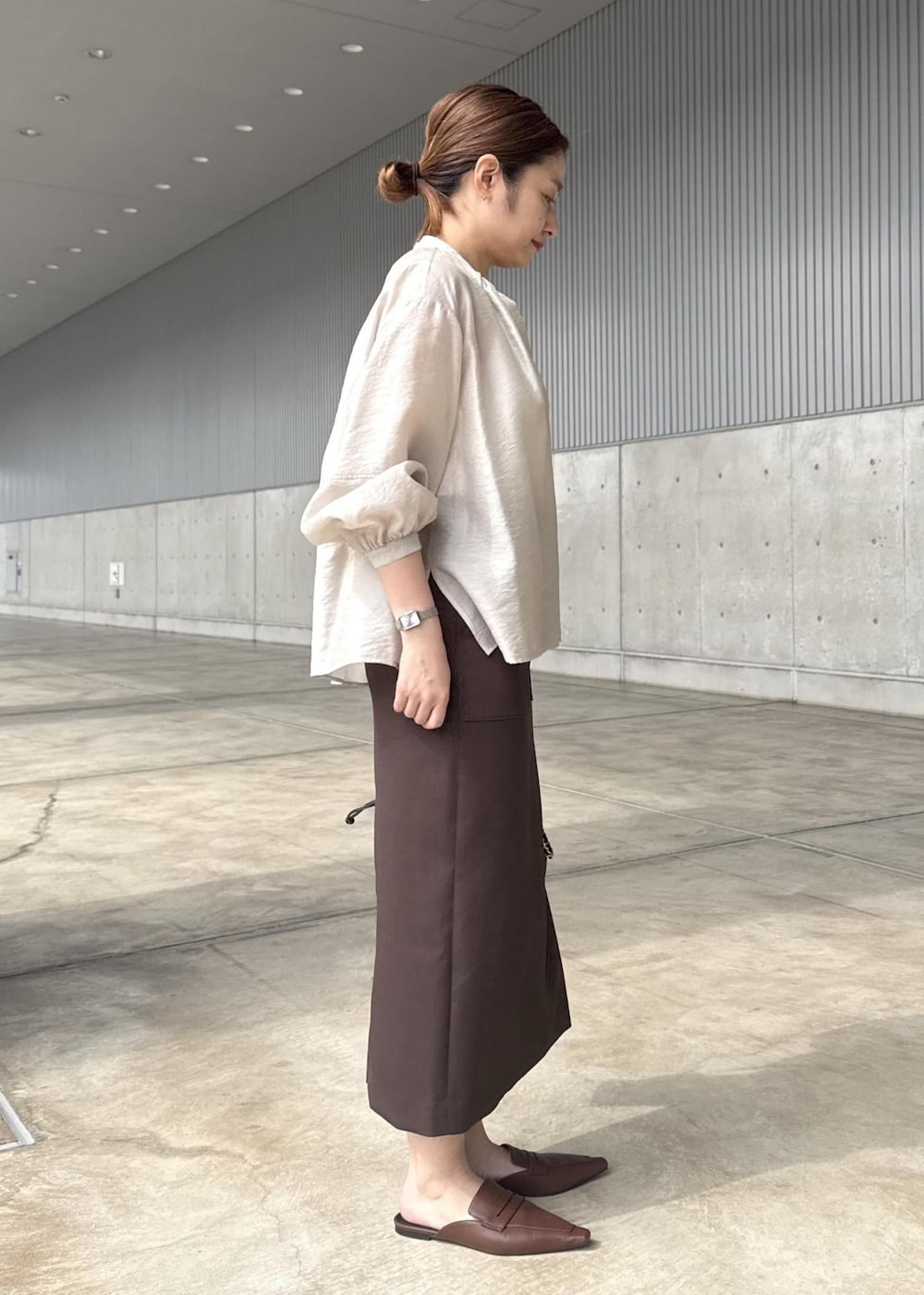 ブラック系のハンドバッグ、ブラウン系のスカート、ベージュ系のシャツ/ブラウスを着用したレディースの春コーディネートの2枚目の写真