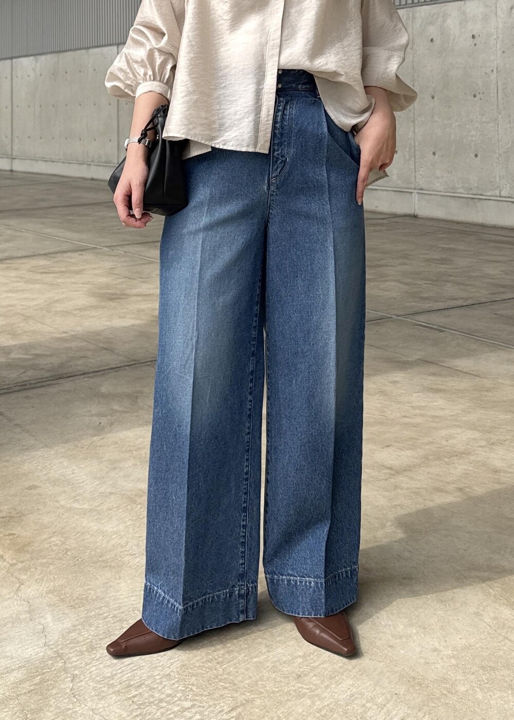 ブルー系のデニムパンツ、ブラック系のハンドバッグ、ベージュ系のシャツ/ブラウスを着用したレディースの春コーディネートの6枚目の写真