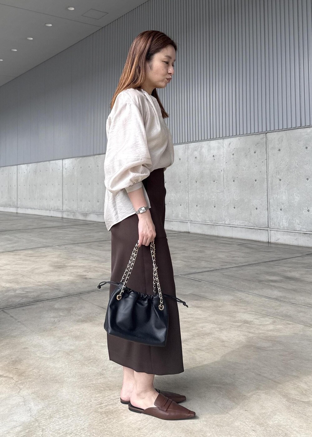 ブラック系のハンドバッグ、ブラウン系のスカート、ベージュ系のシャツ/ブラウスを着用したレディースの春コーディネートの7枚目の写真