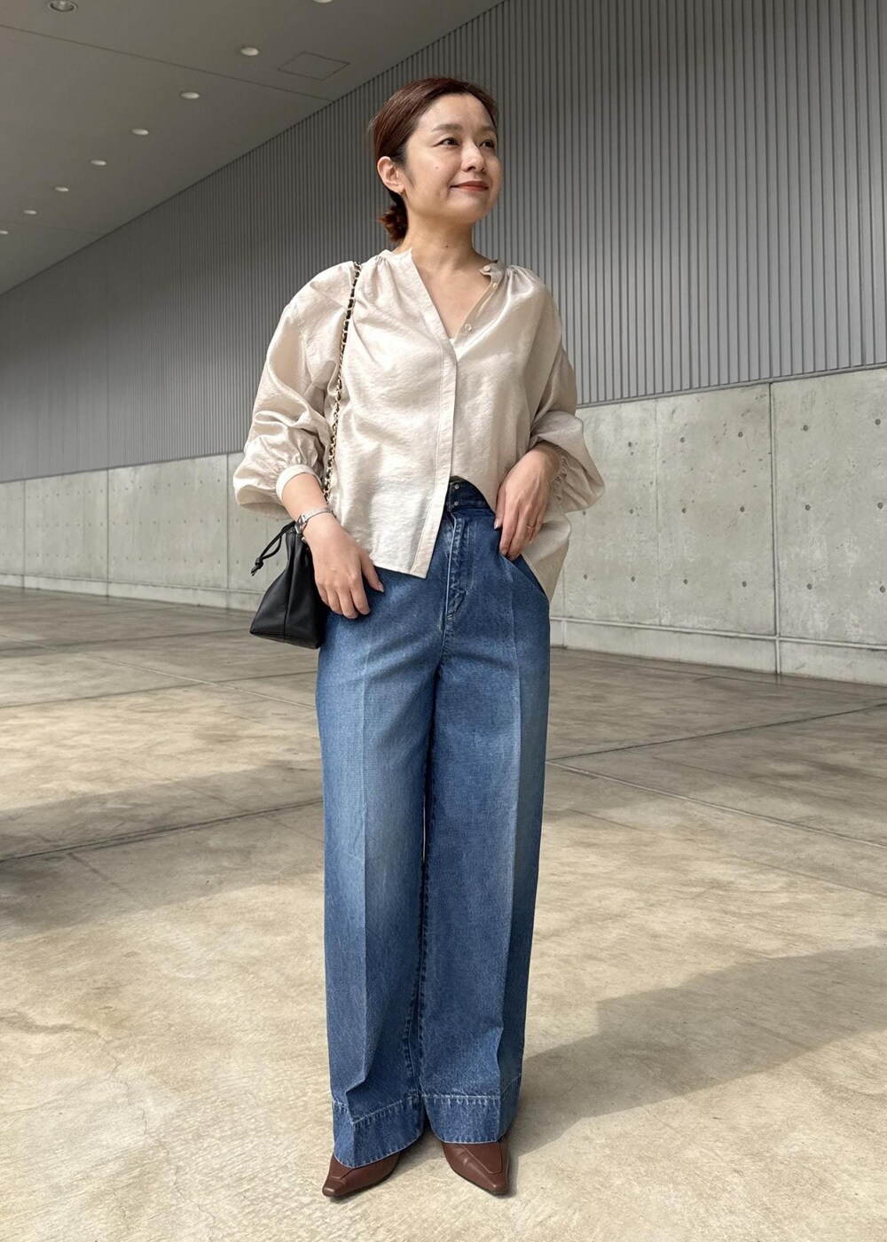 ブルー系のデニムパンツ、ブラック系のハンドバッグ、ベージュ系のシャツ/ブラウスを着用したレディースの春コーディネートの8枚目の写真