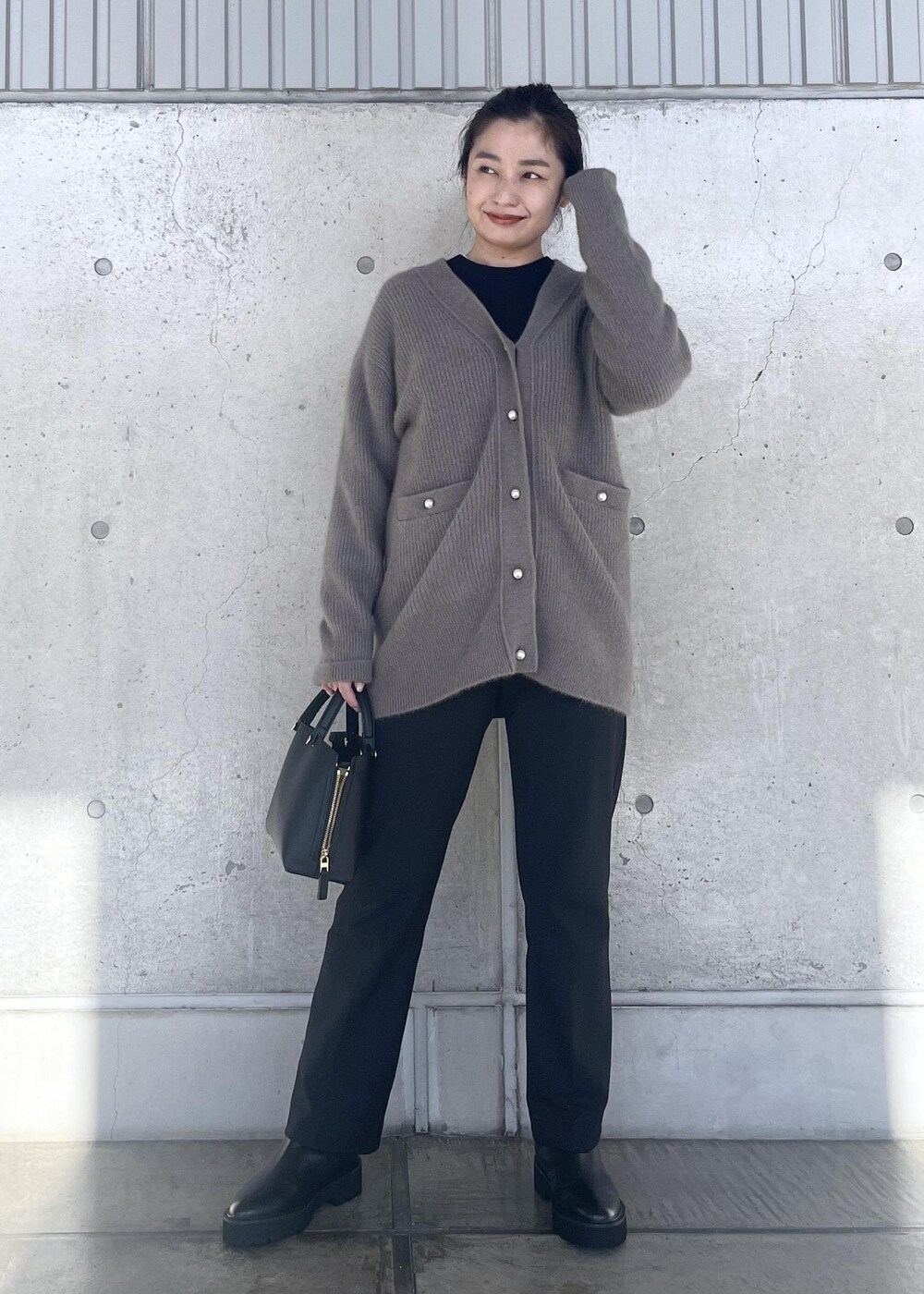 ブラック系のハンドバッグ、ブラック系のブーツ、ブラウン系のカーディガン/ボレロを着用したレディースの冬コーディネートの6枚目の写真