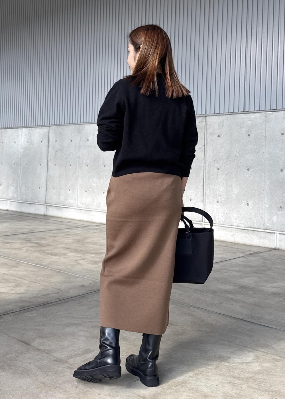 ブラウン系のスカート、ブラック系のカーディガン/ボレロ、ホワイト系のTシャツ/カットソーを着用したレディースの冬コーディネートの3枚目の写真