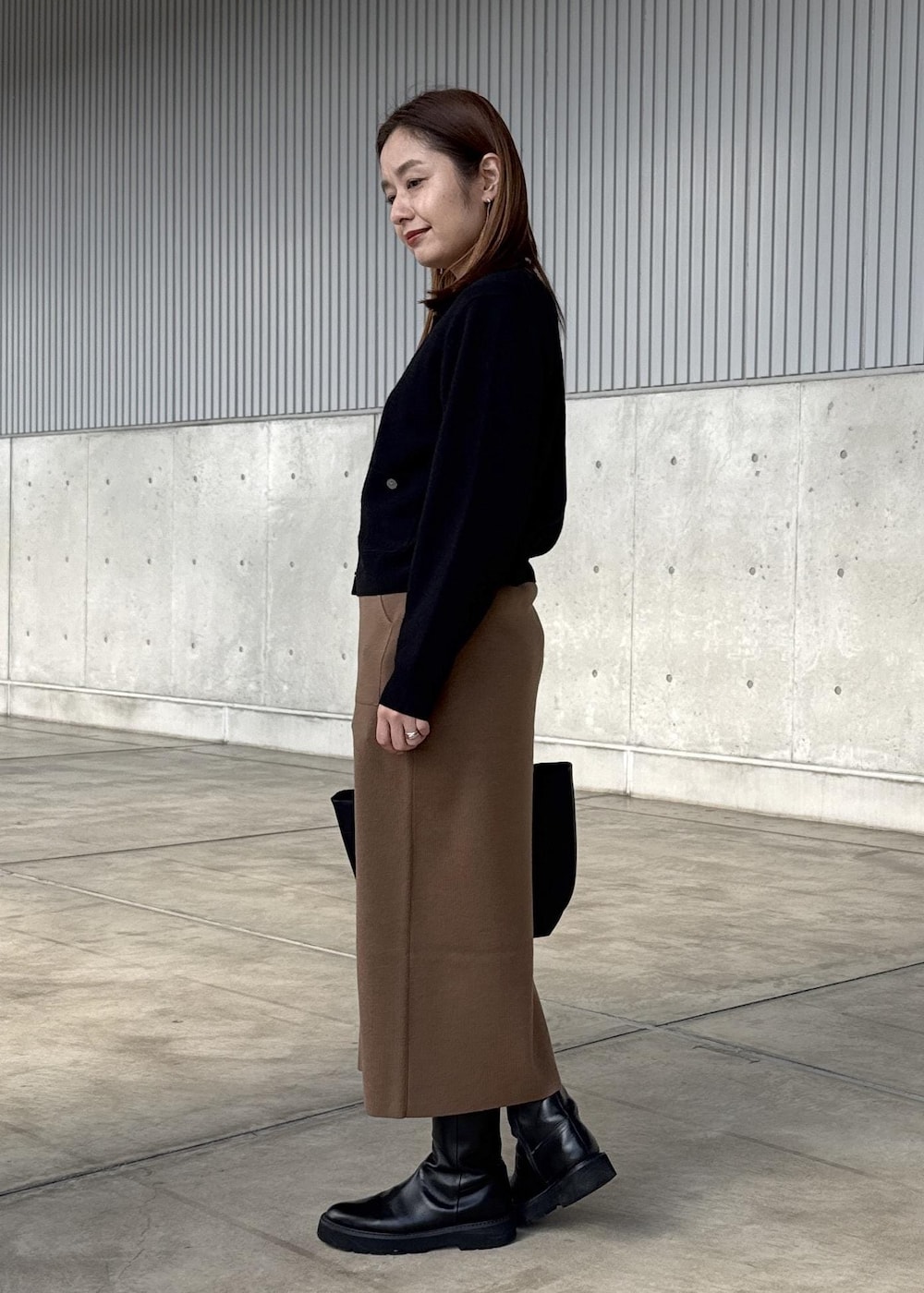 ブラウン系のスカート、ブラック系のカーディガン/ボレロ、ホワイト系のTシャツ/カットソーを着用したレディースの冬コーディネートの2枚目の写真