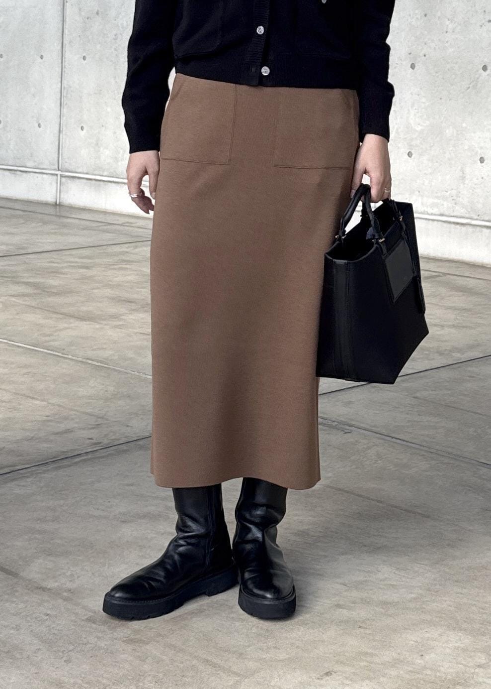 ブラウン系のスカート、ブラック系のカーディガン/ボレロ、ホワイト系のTシャツ/カットソーを着用したレディースの冬コーディネートの4枚目の写真