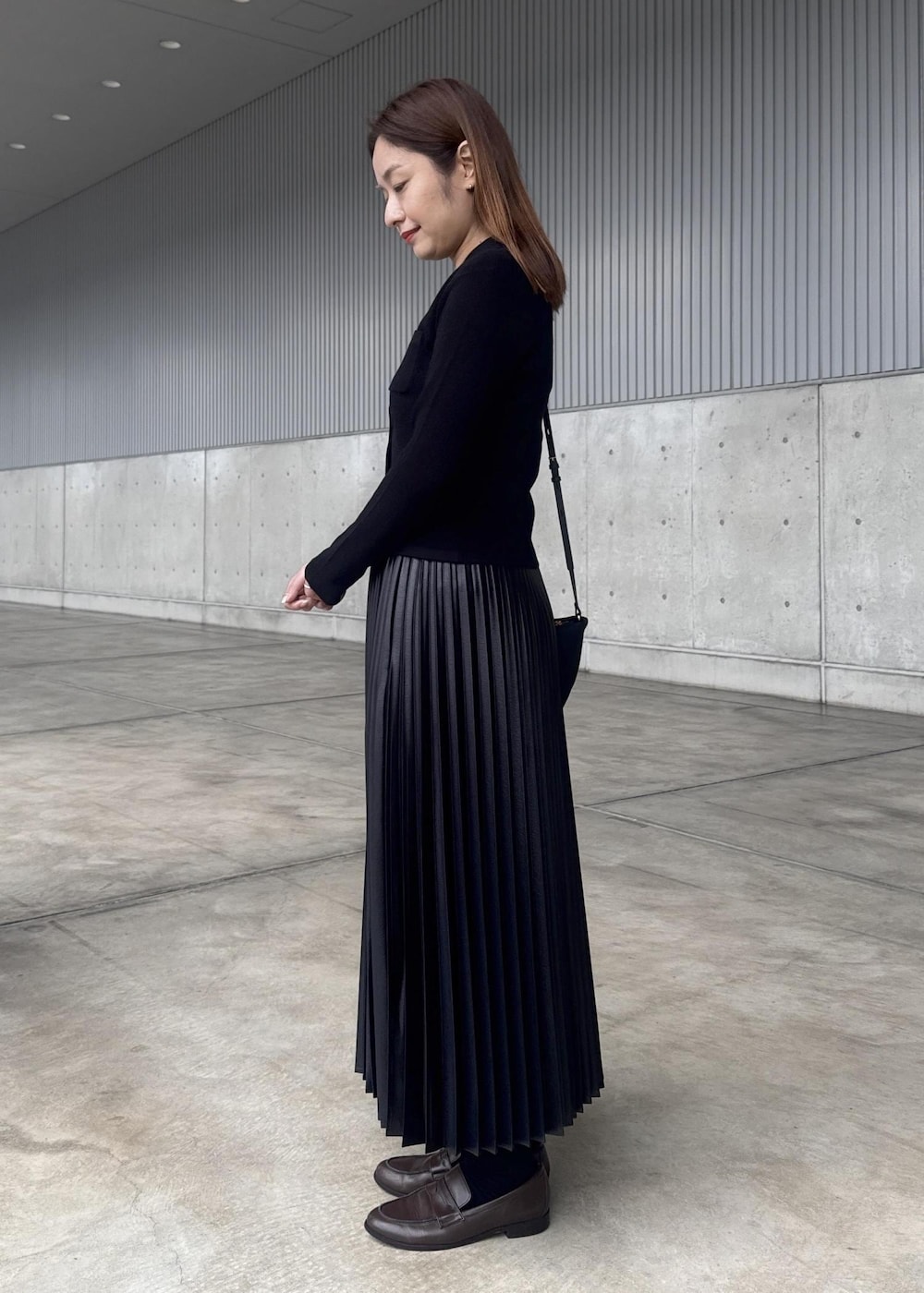 ブラック系のスカート、ブラック系のショルダーバッグ、ベージュ系のトレンチコートを着用したレディースの春コーディネートの3枚目の写真