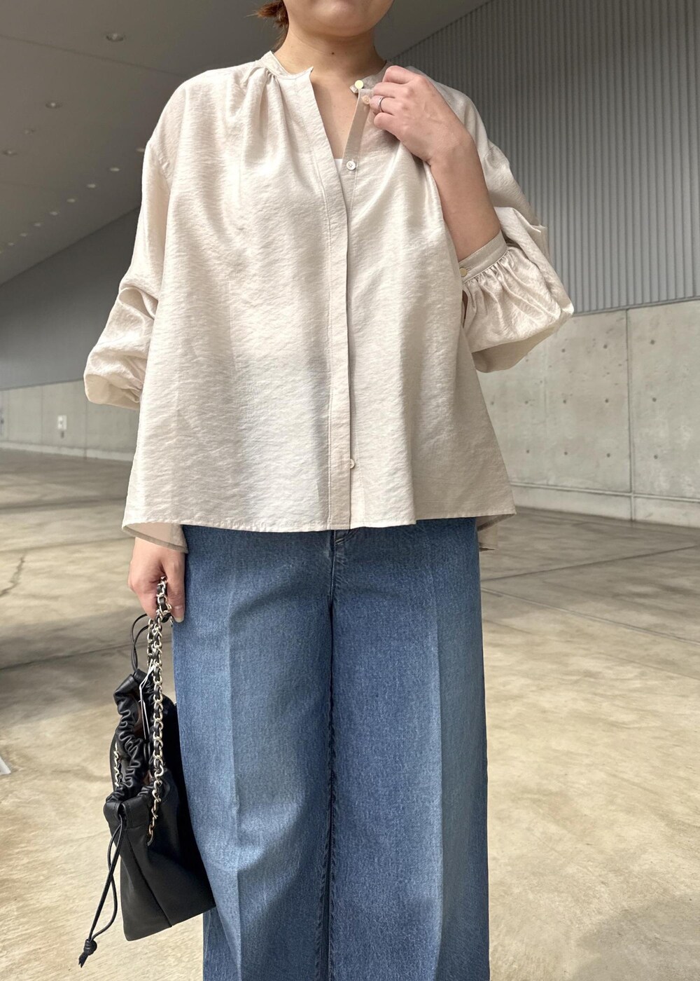 ブルー系のデニムパンツ、ブラック系のハンドバッグ、ベージュ系のシャツ/ブラウスを着用したレディースの春コーディネートの5枚目の写真