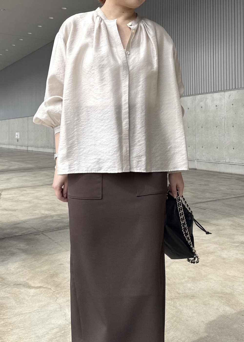 ブラック系のハンドバッグ、ブラウン系のスカート、ベージュ系のシャツ/ブラウスを着用したレディースの春コーディネートの4枚目の写真