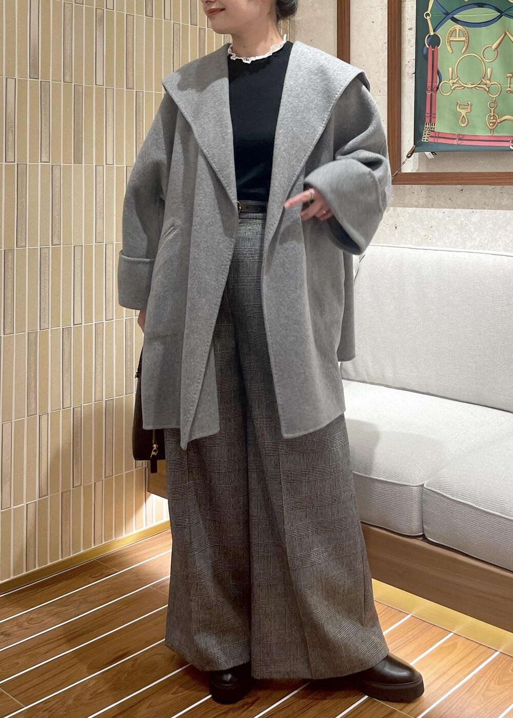 ブラウン系のハンドバッグ、グレー系のその他アウター、ブラック系のブーツを着用したレディースの秋コーディネートの7枚目の写真