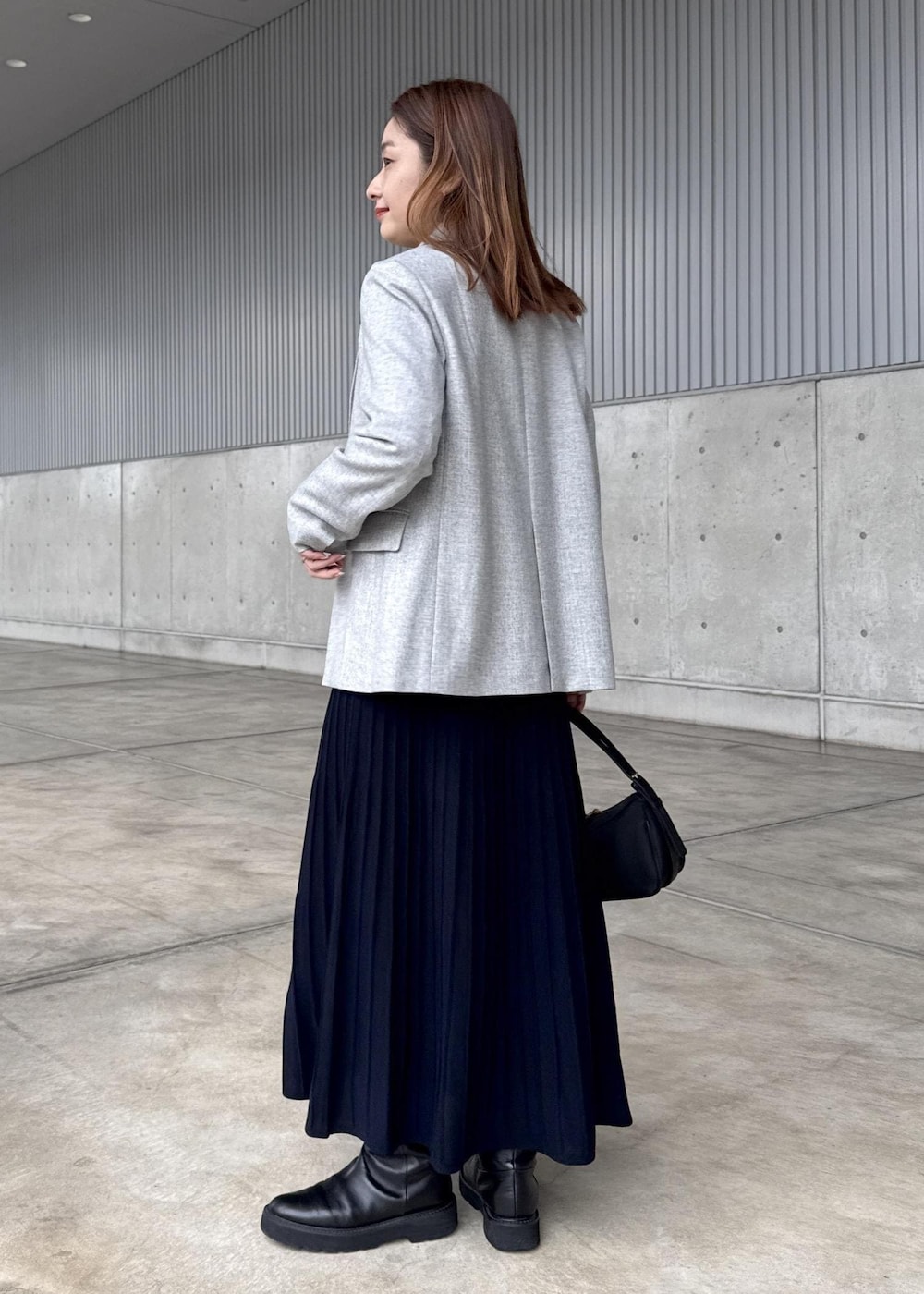 ブラック系のハンドバッグ、グレー系のテーラードジャケット、ブルー系のドレスを着用したレディースの冬コーディネートの3枚目の写真